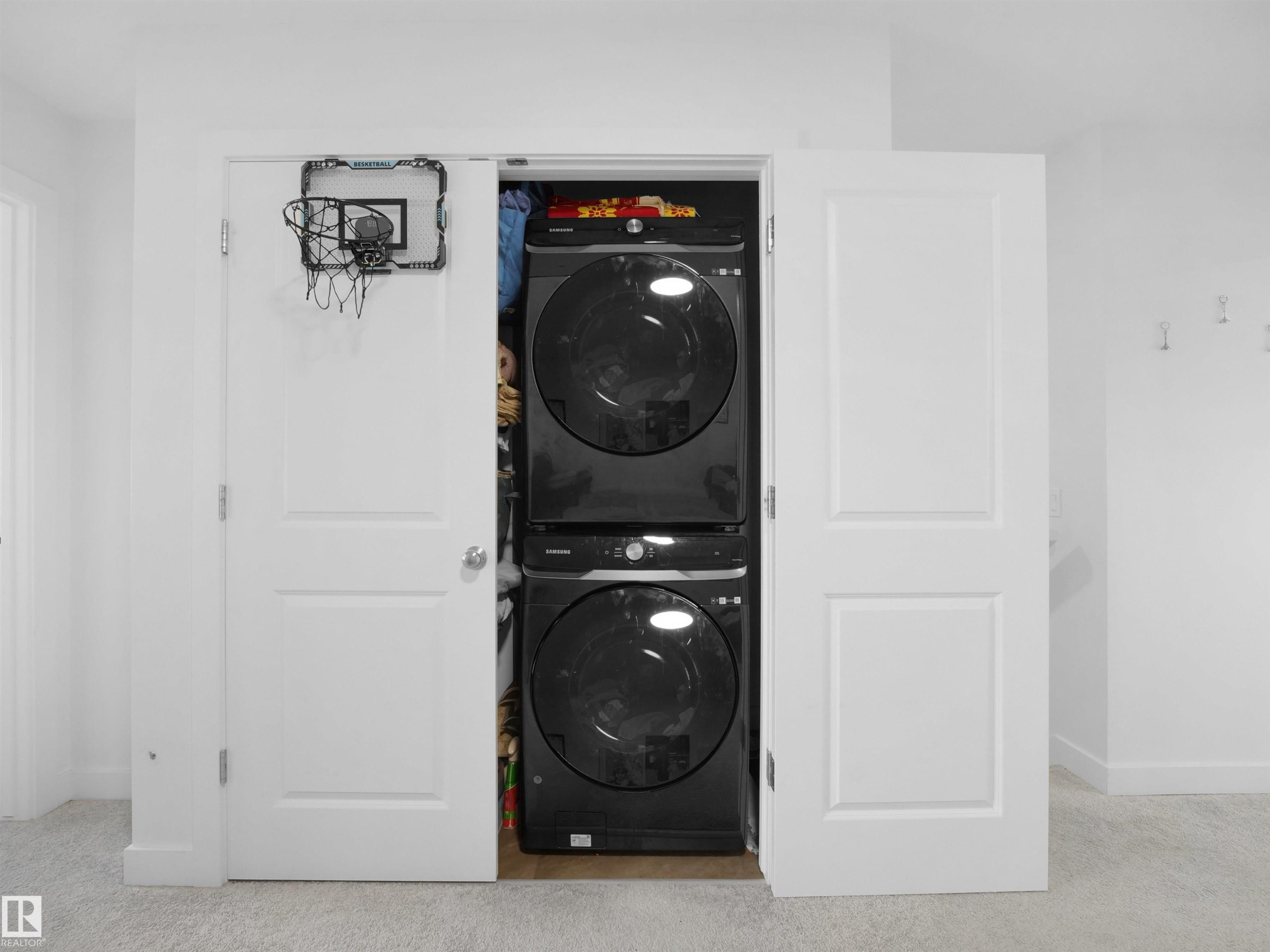 Laundry closet featuring a stacked black washer and dryer unit - 19316 29 Avenue, Edmonton, AB