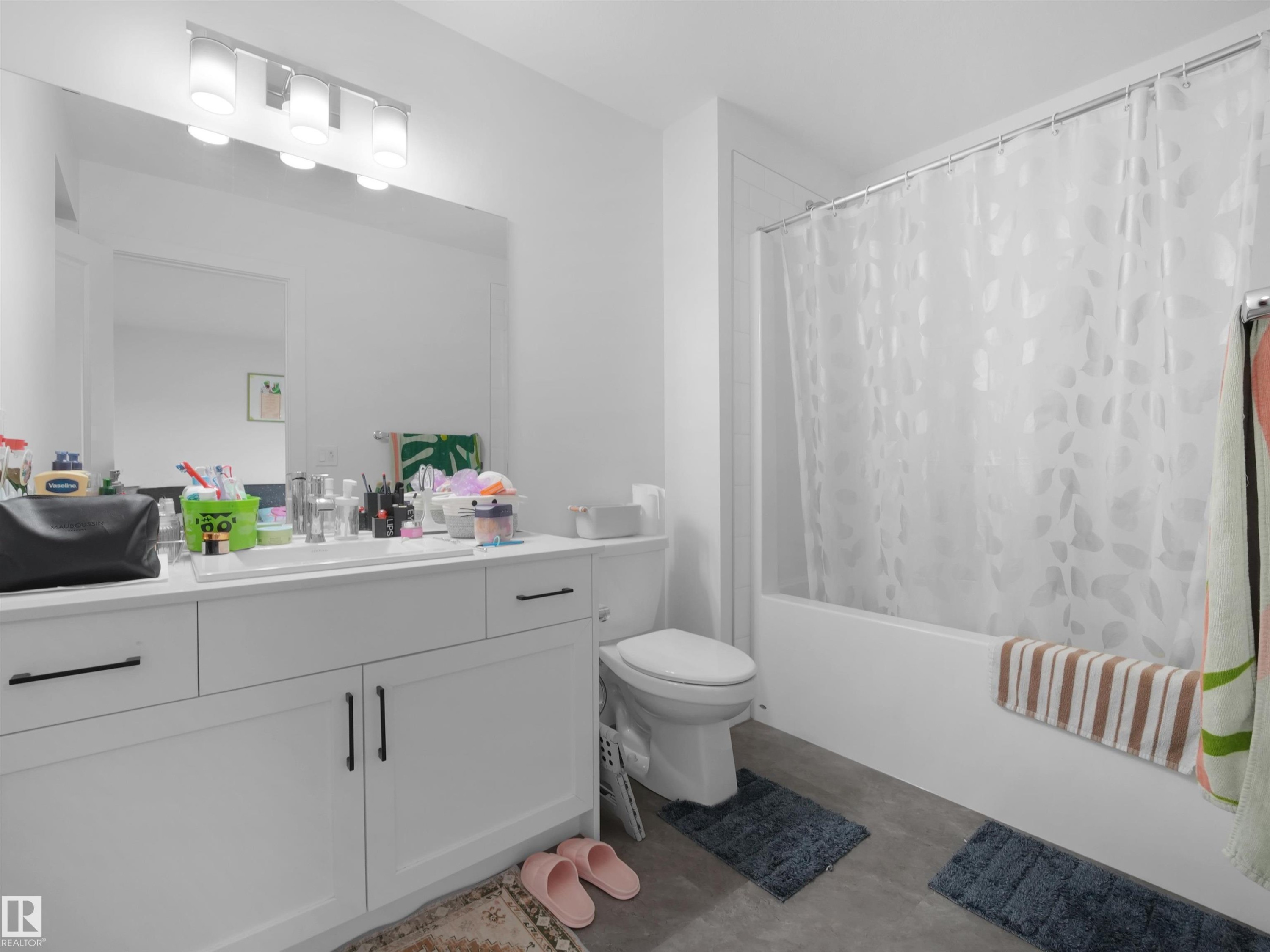 Bathroom featuring a white vanity with integrated sink, a rectangular mirror, and a four-light vanity fixture - 19316 29 Avenue, Edmonton, AB