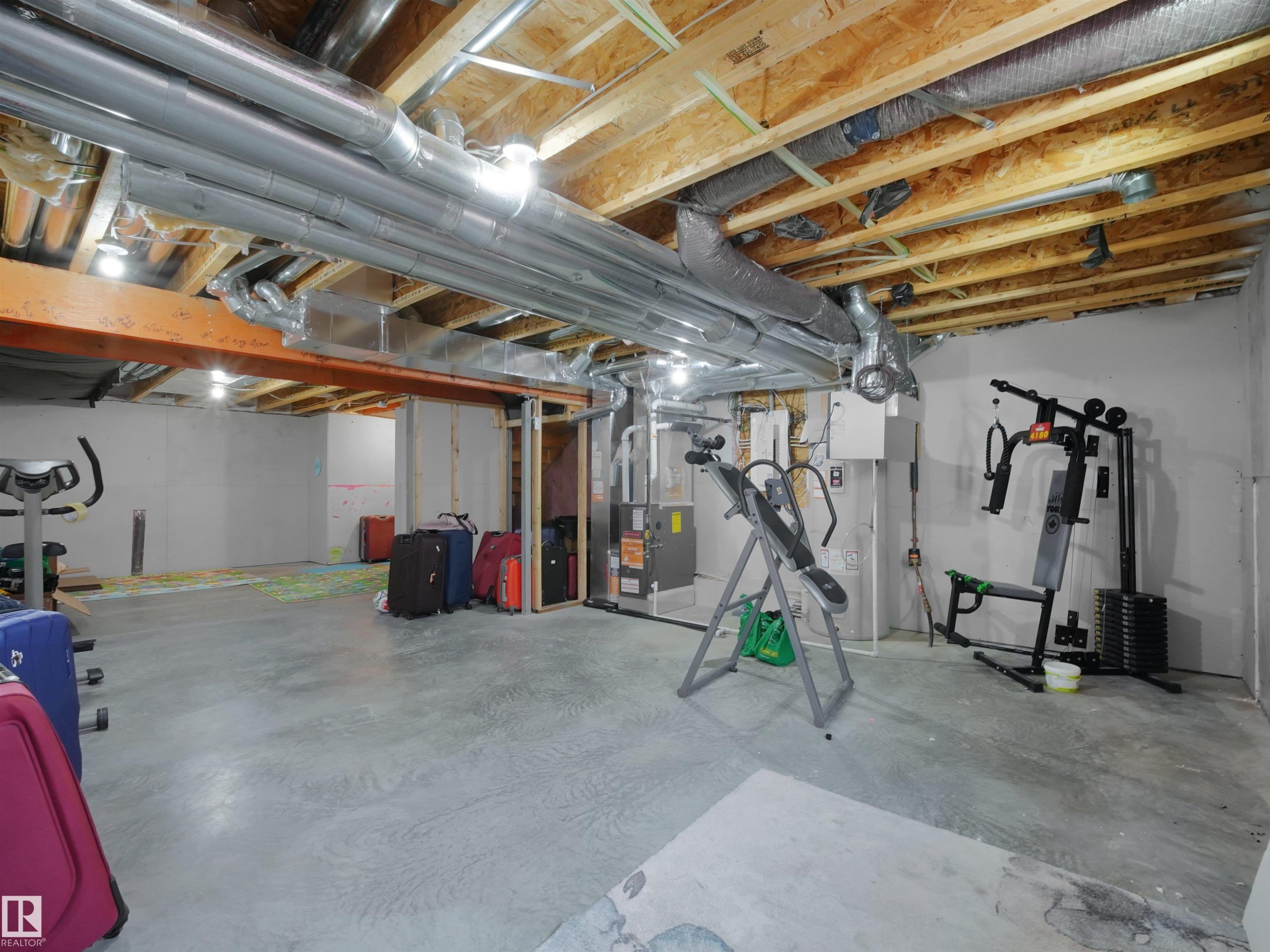 Unfinished basement area featuring exposed ceiling joists, overhead ductwork, concrete flooring, and partial framing - 19316 29 Avenue, Edmonton, AB