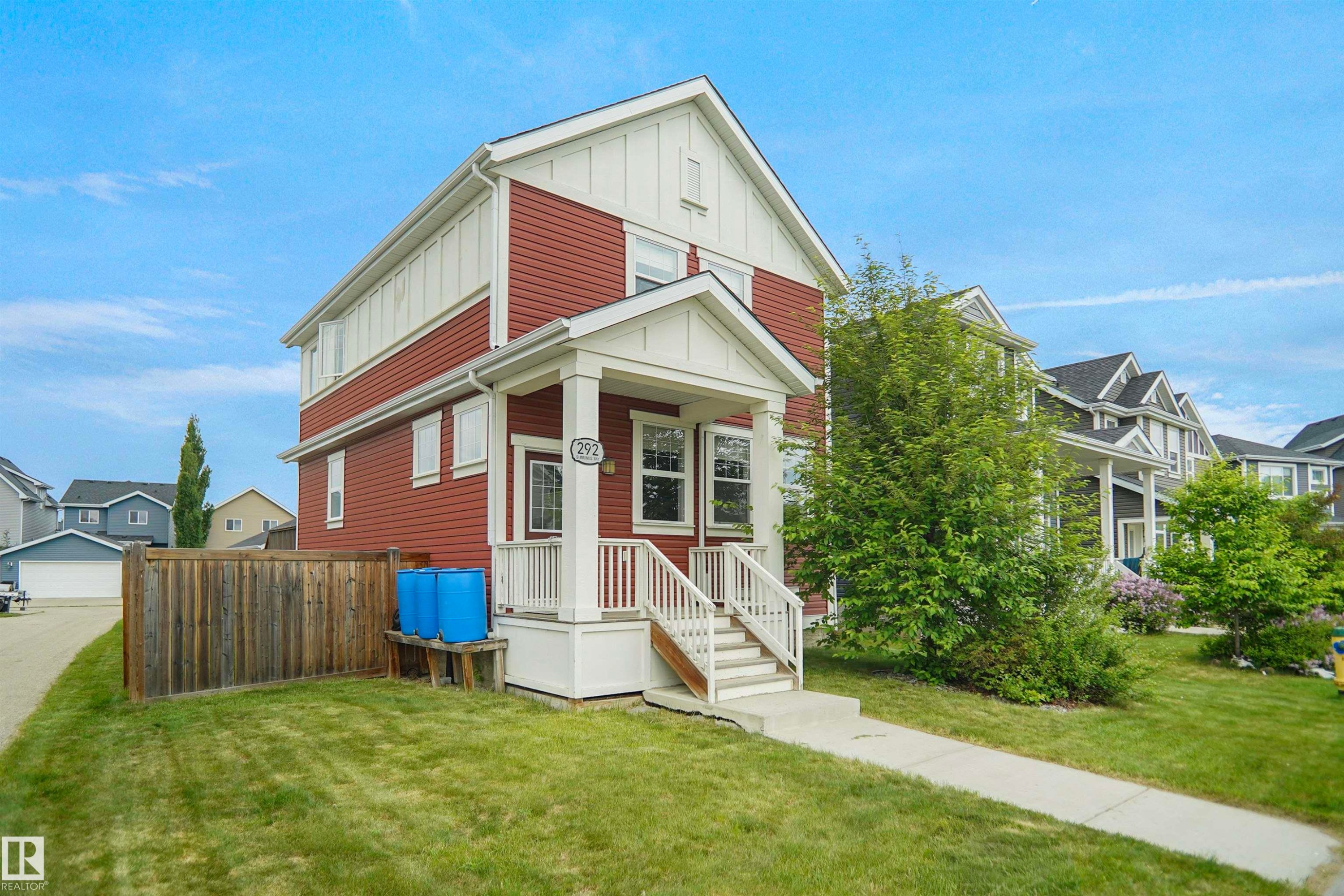 Two-story residence featuring red siding and white trim - 292 Simmonds Way, Leduc, AB