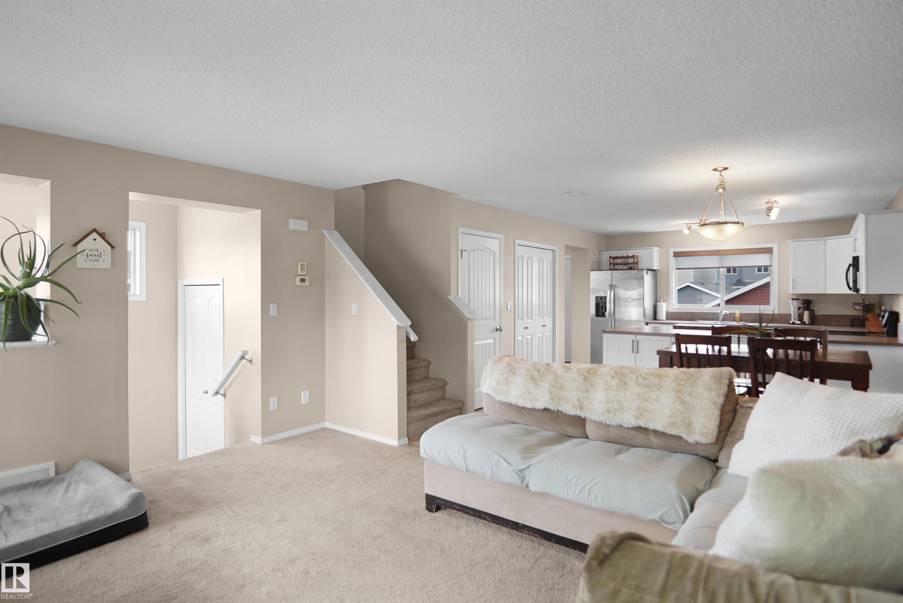 Expansive open-concept living area featuring neutral-toned carpeting and walls - 292 Simmonds Way, Leduc, AB