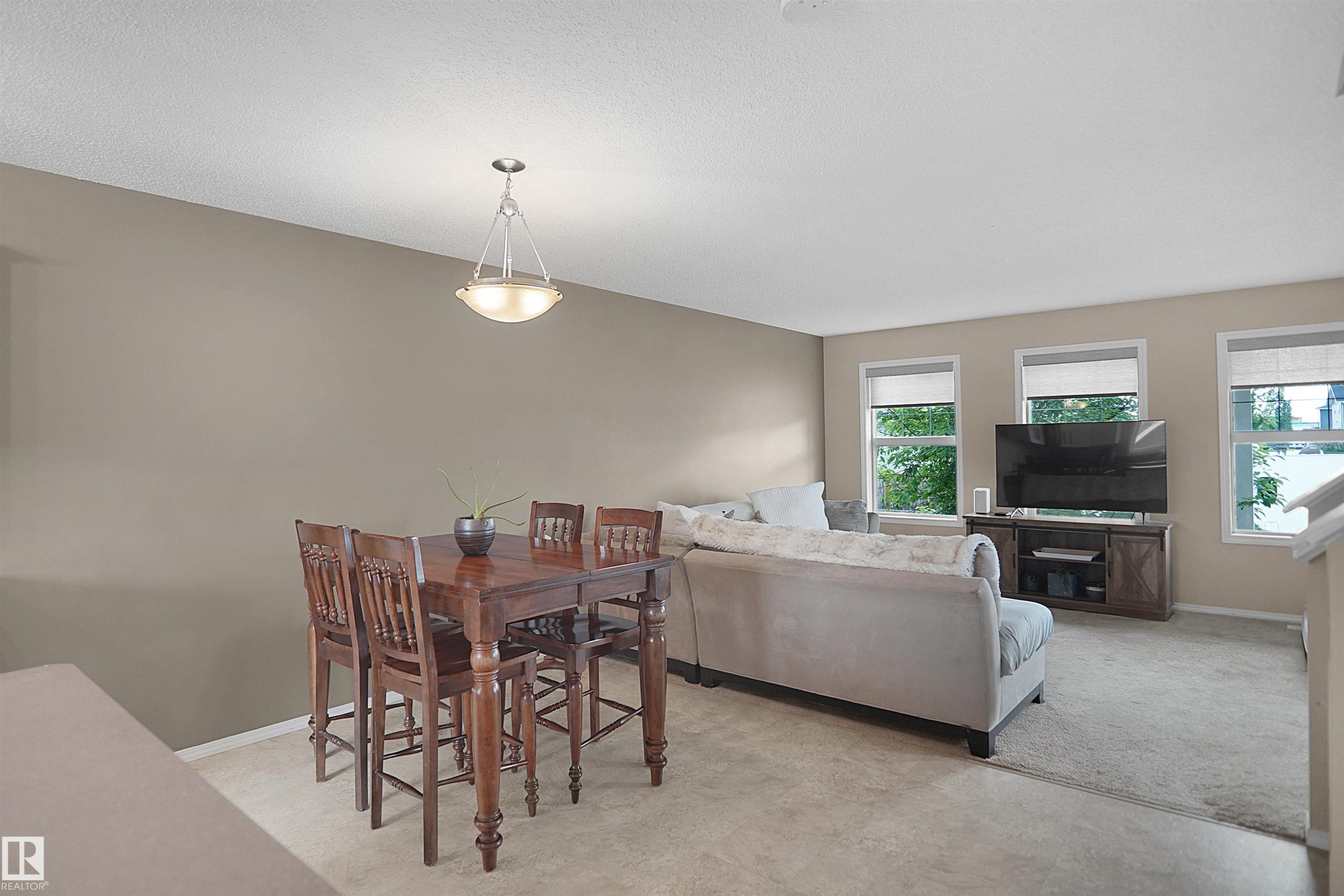 Open-concept living area with neutral wall tones and light-toned carpeting - 292 Simmonds Way, Leduc, AB