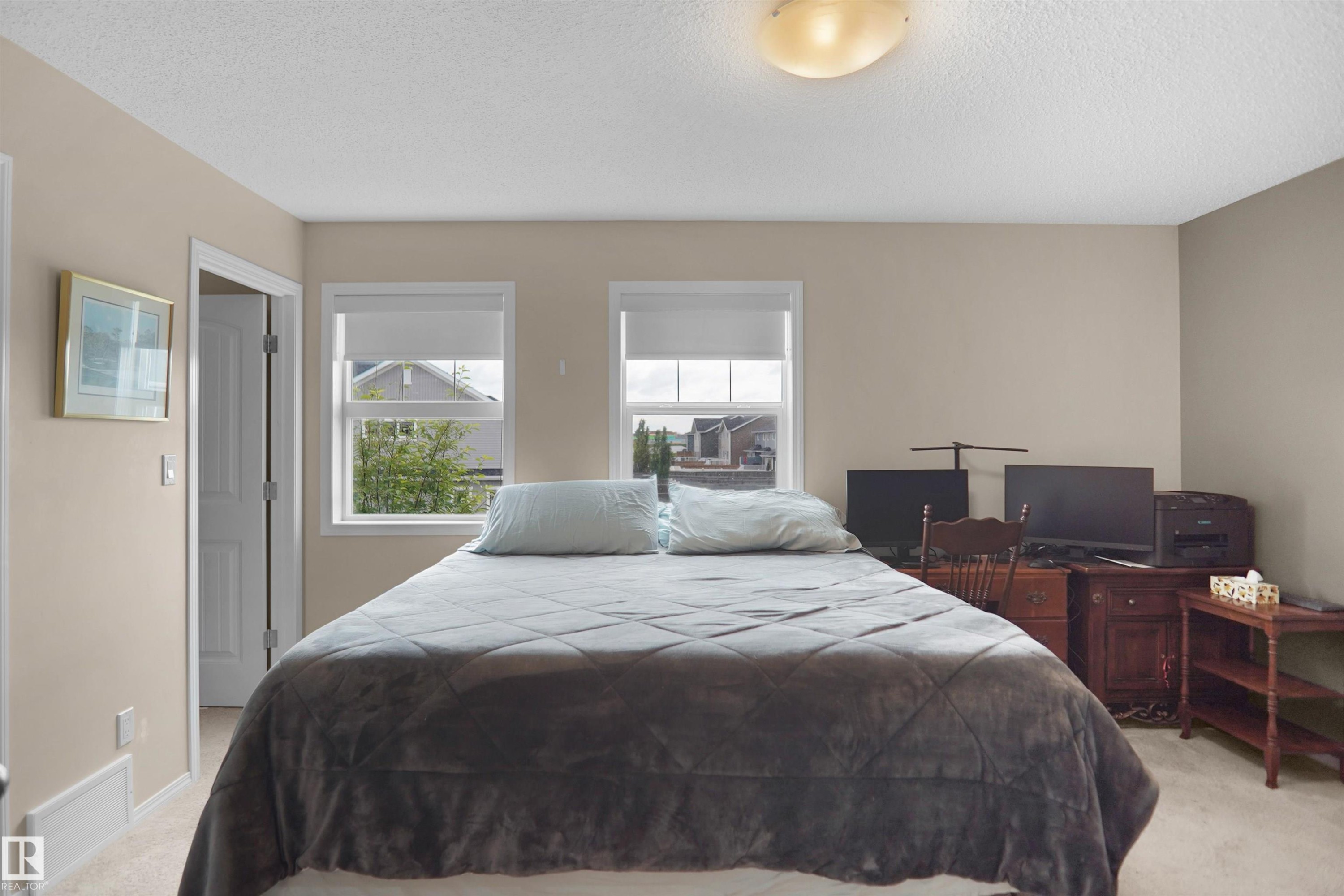 Carpeted room with neutral-toned walls, two windows featuring window treatments, a white door frame, and an overhead flush-mount light fixture - 292 Simmonds Way, Leduc, AB