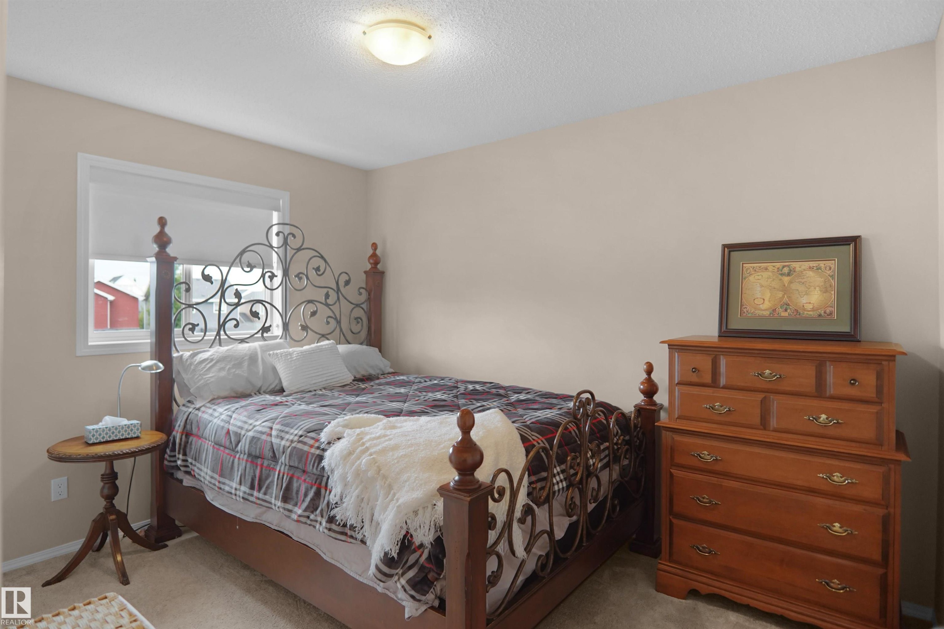Neutral-toned bedroom featuring carpet flooring and a flush-mount ceiling light fixture - 292 Simmonds Way, Leduc, AB