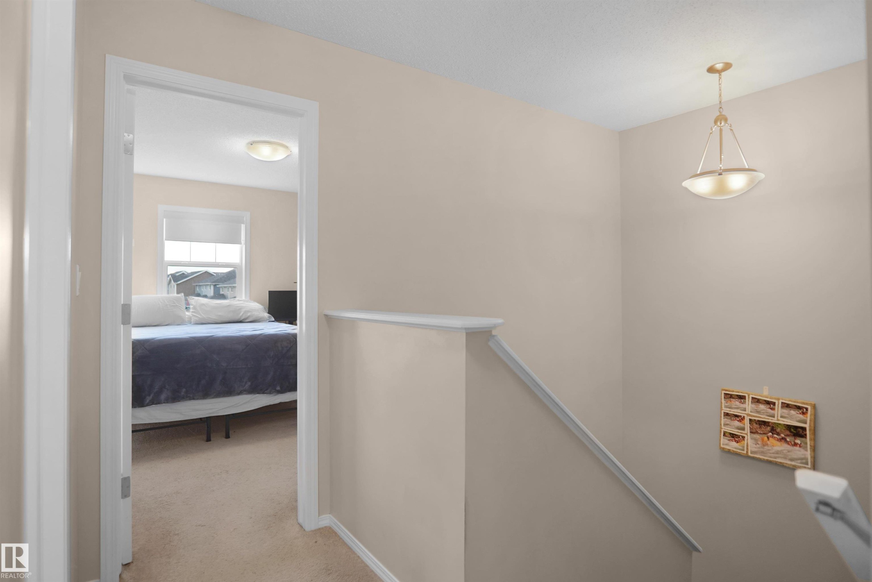 Upper-level landing featuring a hanging light fixture and access to a carpeted room with a window and flush-mount ceiling light - 292 Simmonds Way, Leduc, AB