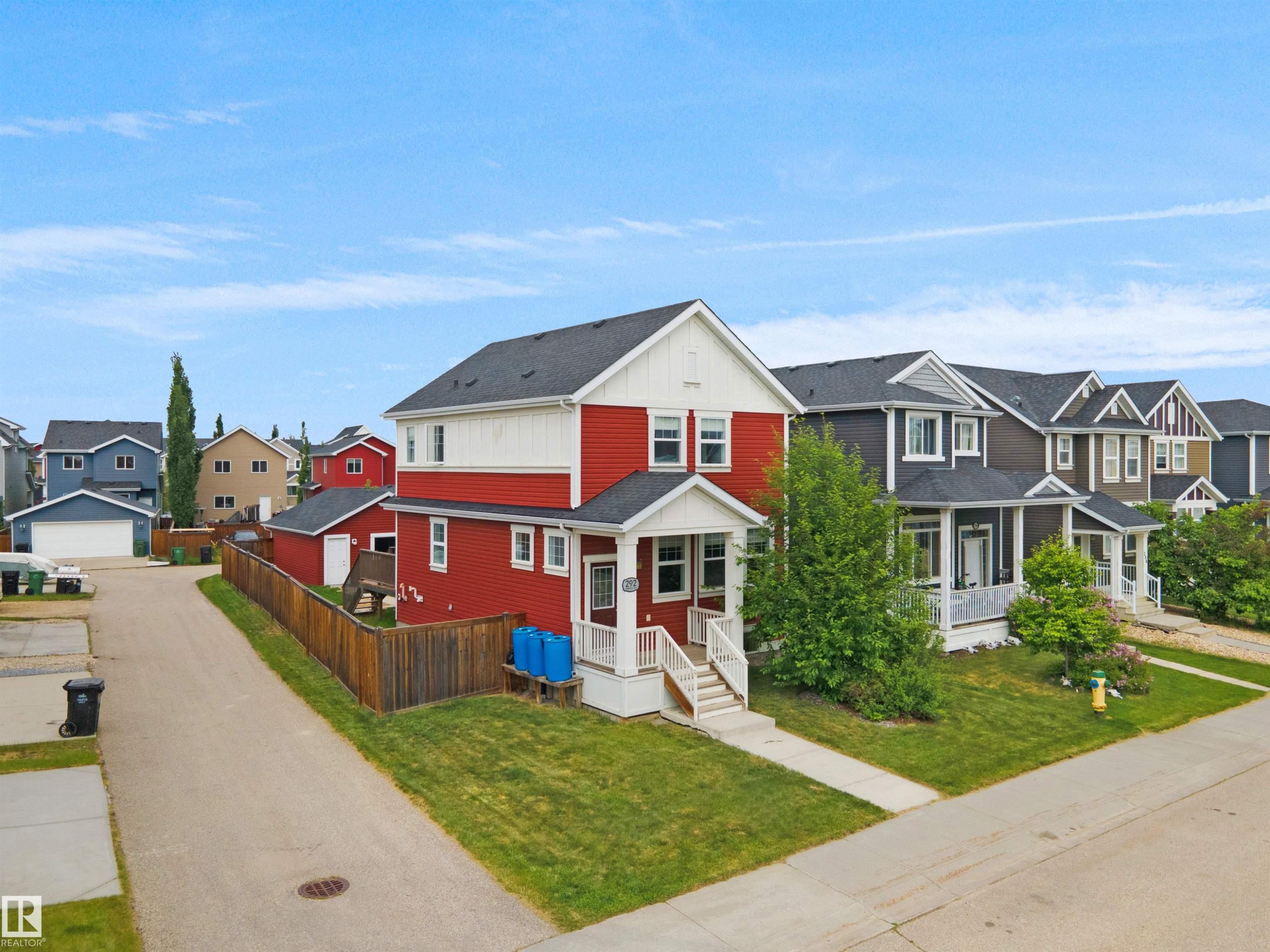Two-story residence featuring a red and white exterior, a covered front porch, and an asphalt shingle roof - 292 Simmonds Way, Leduc, AB