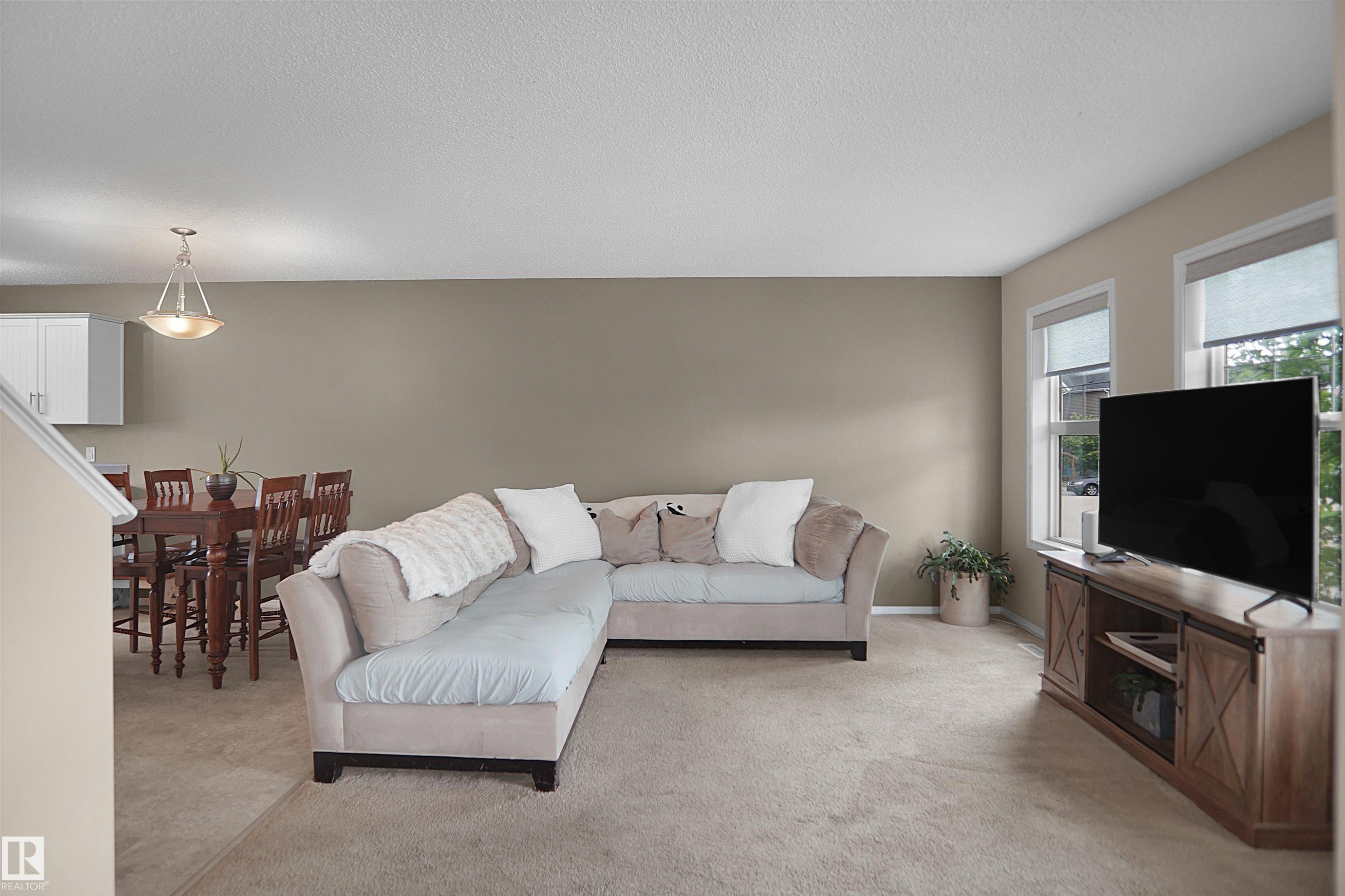 Spacious living area featuring neutral carpeting and ample natural light from multiple windows - 292 Simmonds Way, Leduc, AB