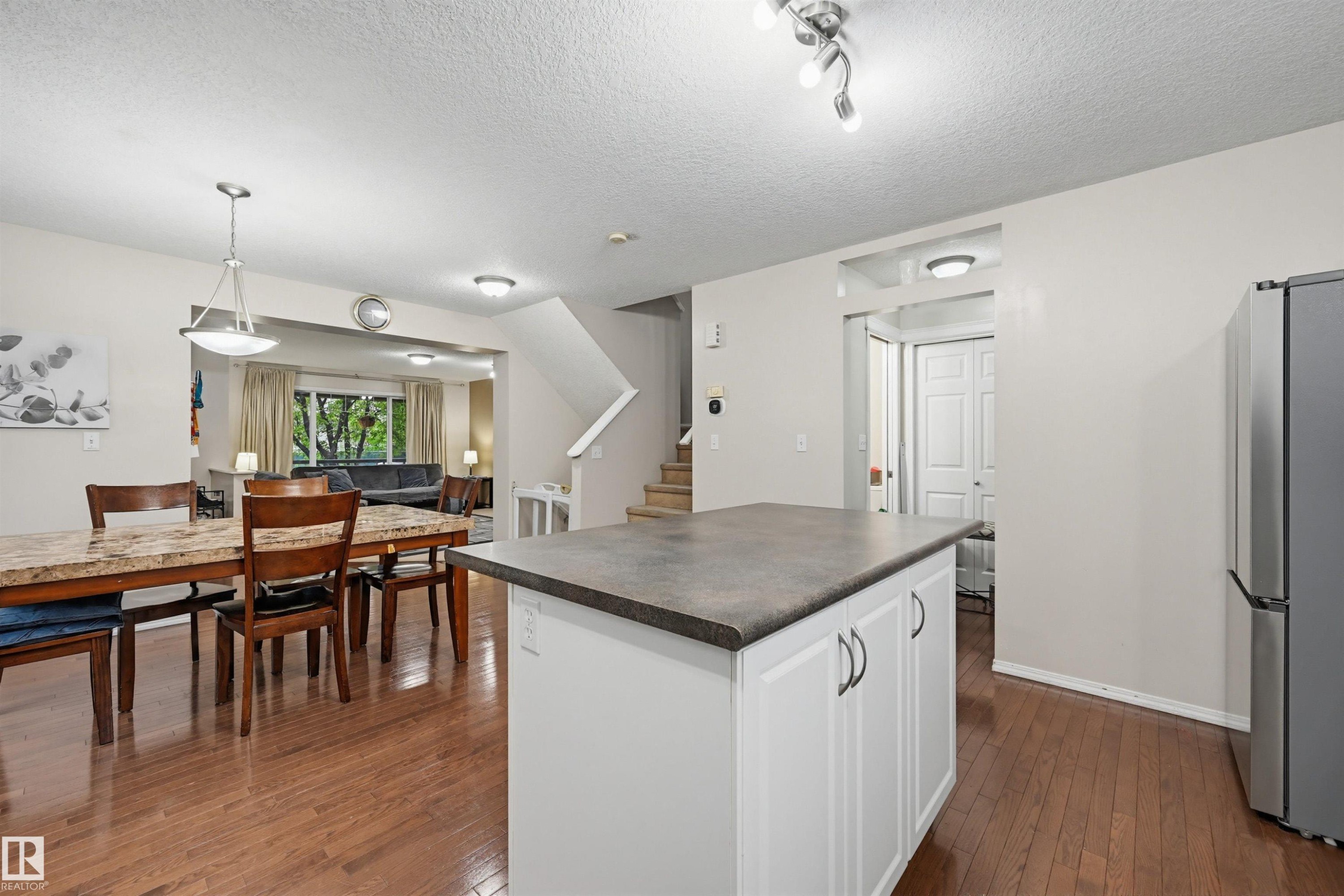 Kitchen island with white cabinetry and dark countertop, wood-finish flooring, and recessed lighting - 1804 121 Street, Edmonton, AB