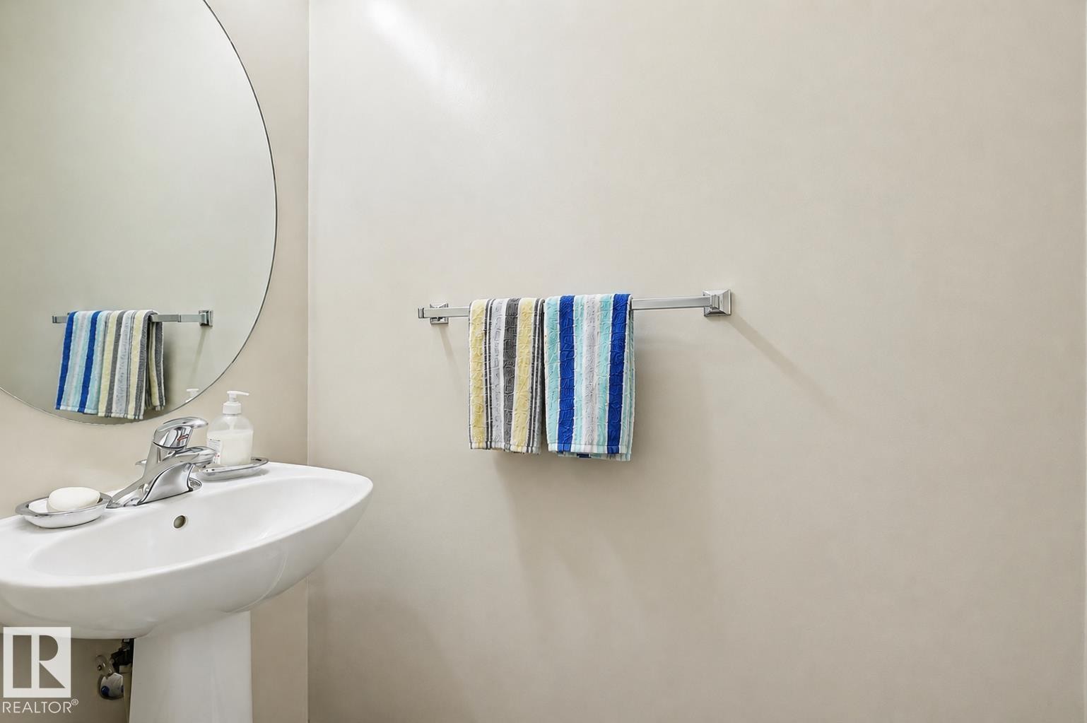 Pedestal sink featuring a polished chrome faucet and a circular wall-mounted mirror - 1804 121 Street, Edmonton, AB