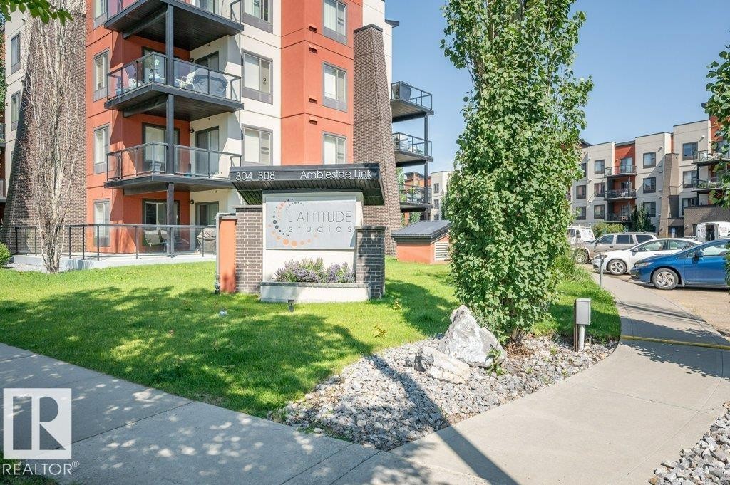 Modern multi-story building featuring a red and grey exterior with multiple balconies - 140 308 Ambleside Link Link, Edmonton, AB