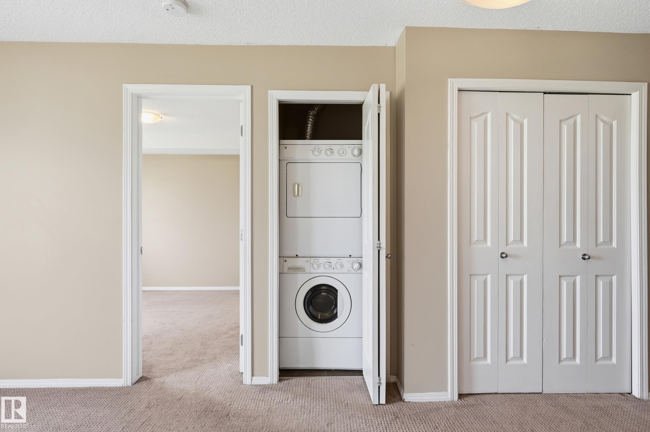 Integrated stackable washer and dryer unit, neutral tone carpeting, and classic white paneled doors - 304 11804 22 Avenue, Edmonton, AB