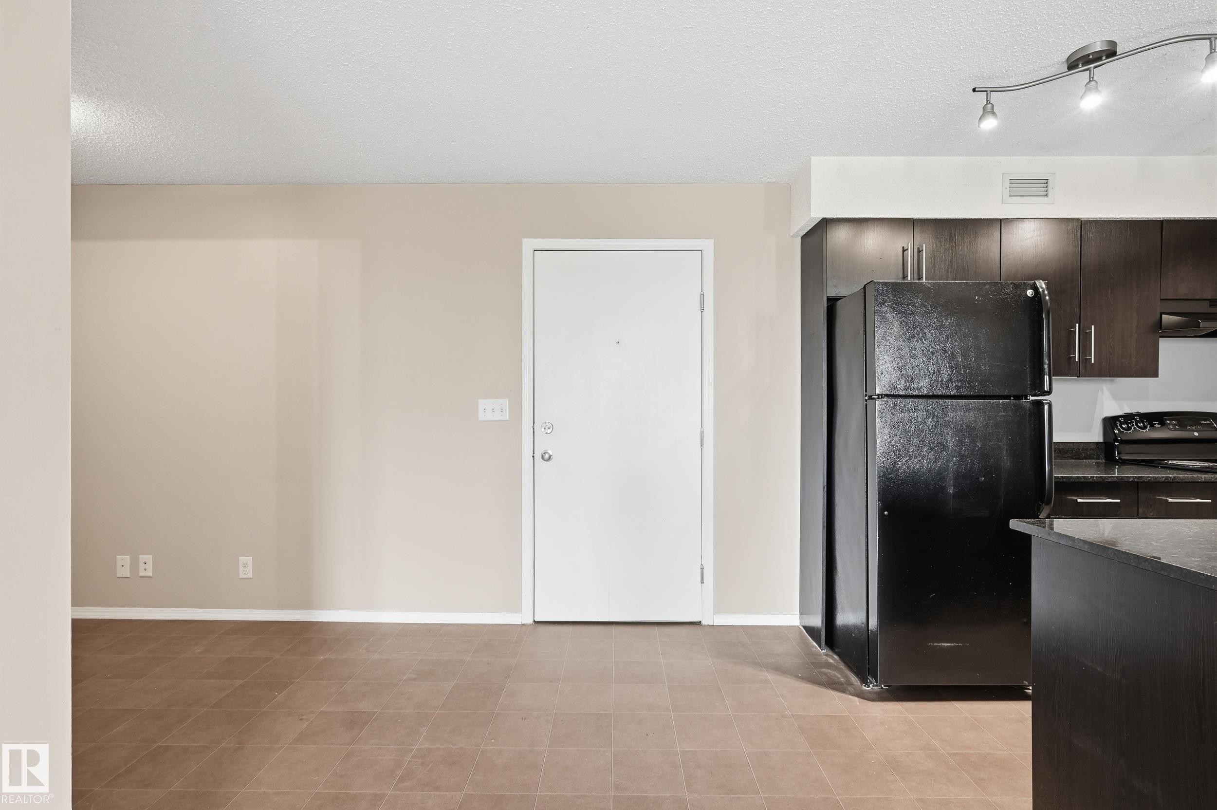Kitchen area featuring dark wood-finish cabinetry, black appliances, and dark countertops - 304 11804 22 Avenue, Edmonton, AB