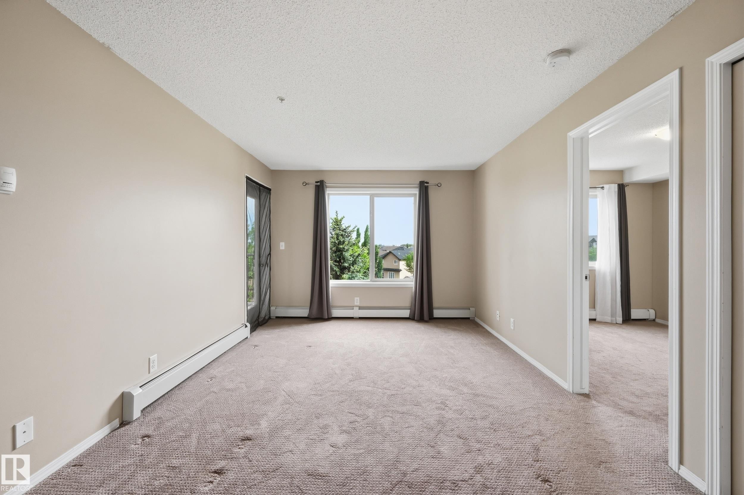 Spacious room featuring neutral carpeting and light beige wall tones - 304 11804 22 Avenue, Edmonton, AB