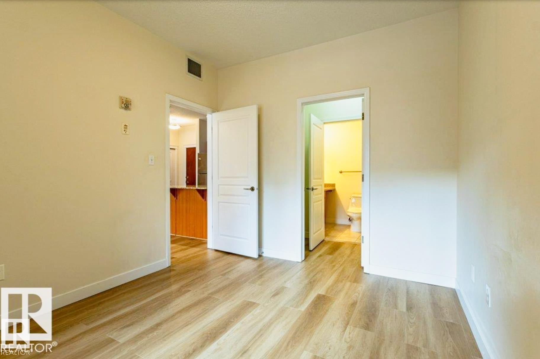 Light wood-finish flooring throughout, complemented by neutral wall tones and white baseboards - #409 10333 112 St Nw, Edmonton, AB - Indoor Photo Showing Other Room