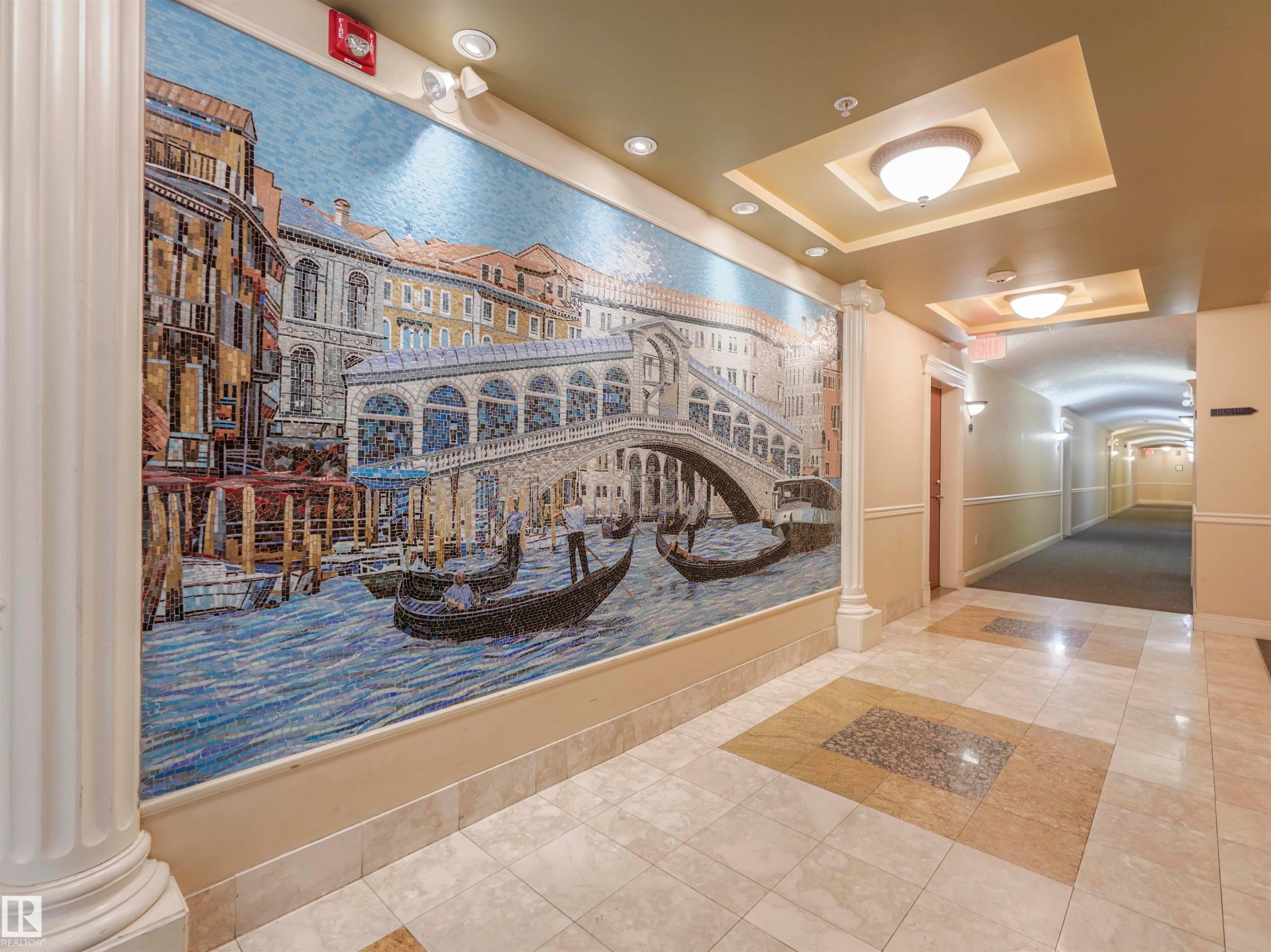 Corridor featuring an expansive wall mosaic art piece, decorative fluted column, coffered ceiling with recessed lighting and dome fixtures, and patterned tile flooring - #409 10333 112 St Nw, Edmonton, AB - Indoor Photo Showing Other Room