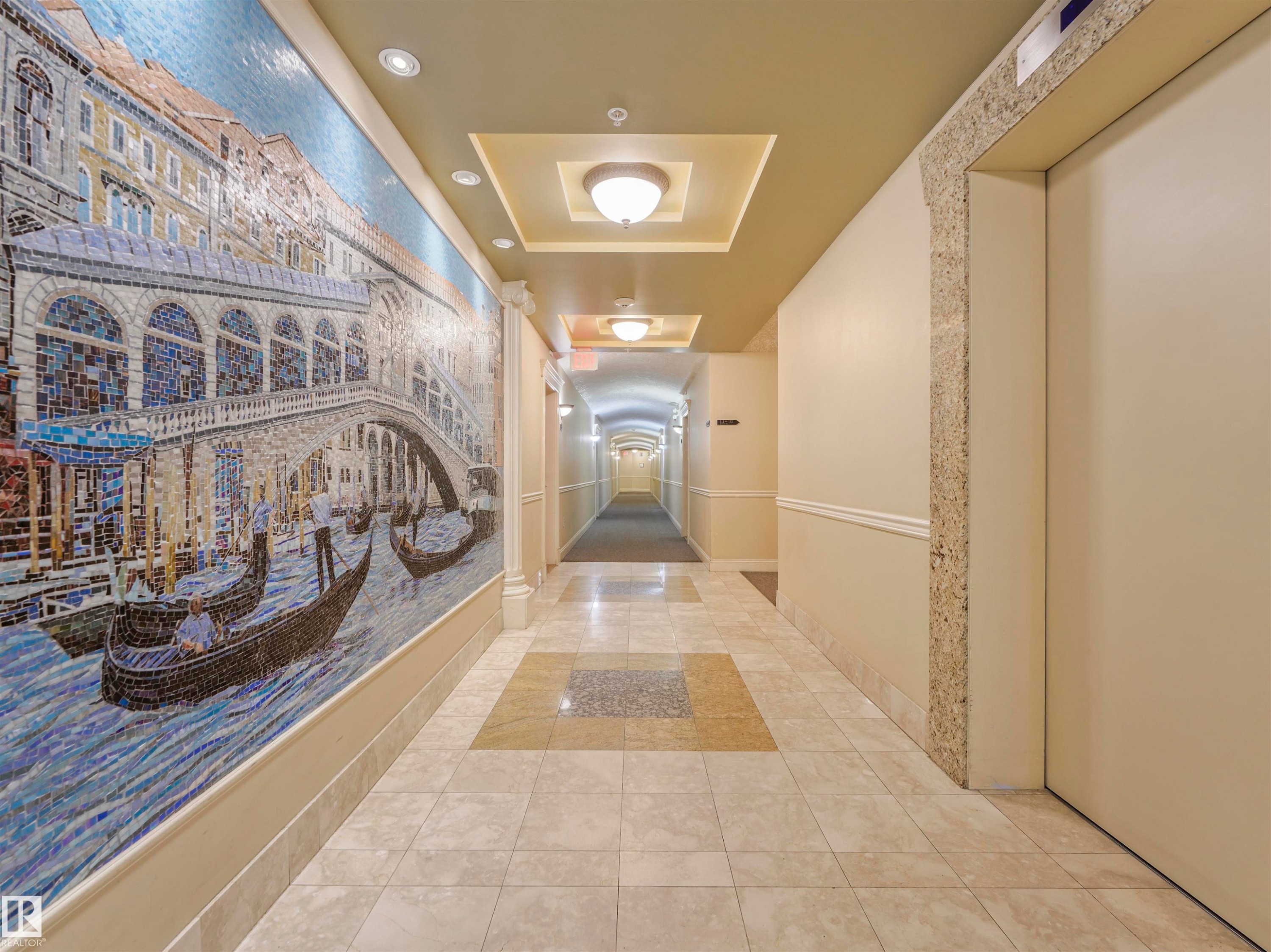 Hallway featuring a detailed mosaic art wall, recessed ceiling lighting, decorative ceiling soffits, tile flooring, and an elevator access point - #409 10333 112 St Nw, Edmonton, AB - Indoor Photo Showing Other Room