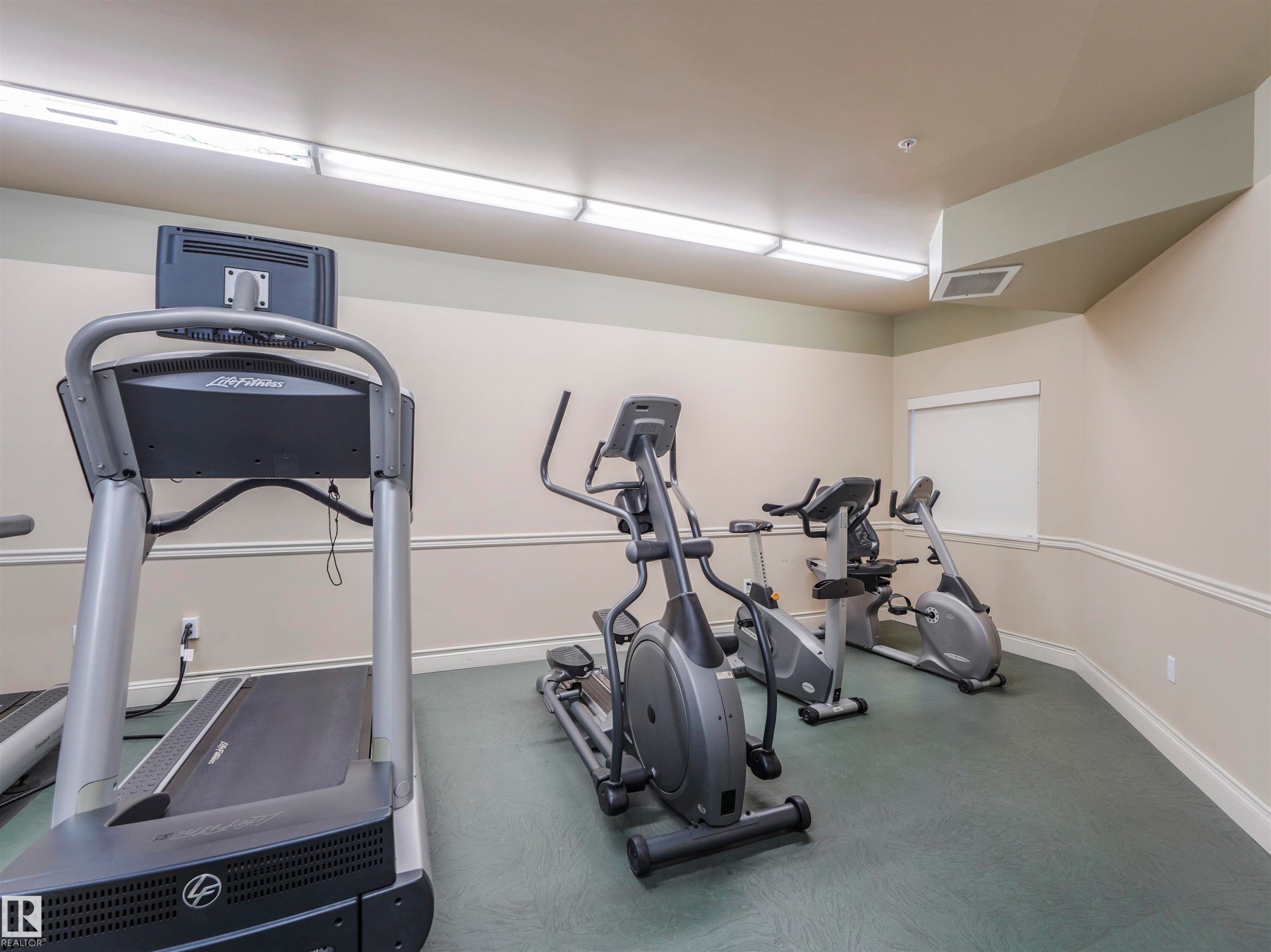 Dedicated fitness space featuring a treadmill, elliptical, and stationary bikes - #409 10333 112 St Nw, Edmonton, AB - Indoor Photo Showing Gym Room