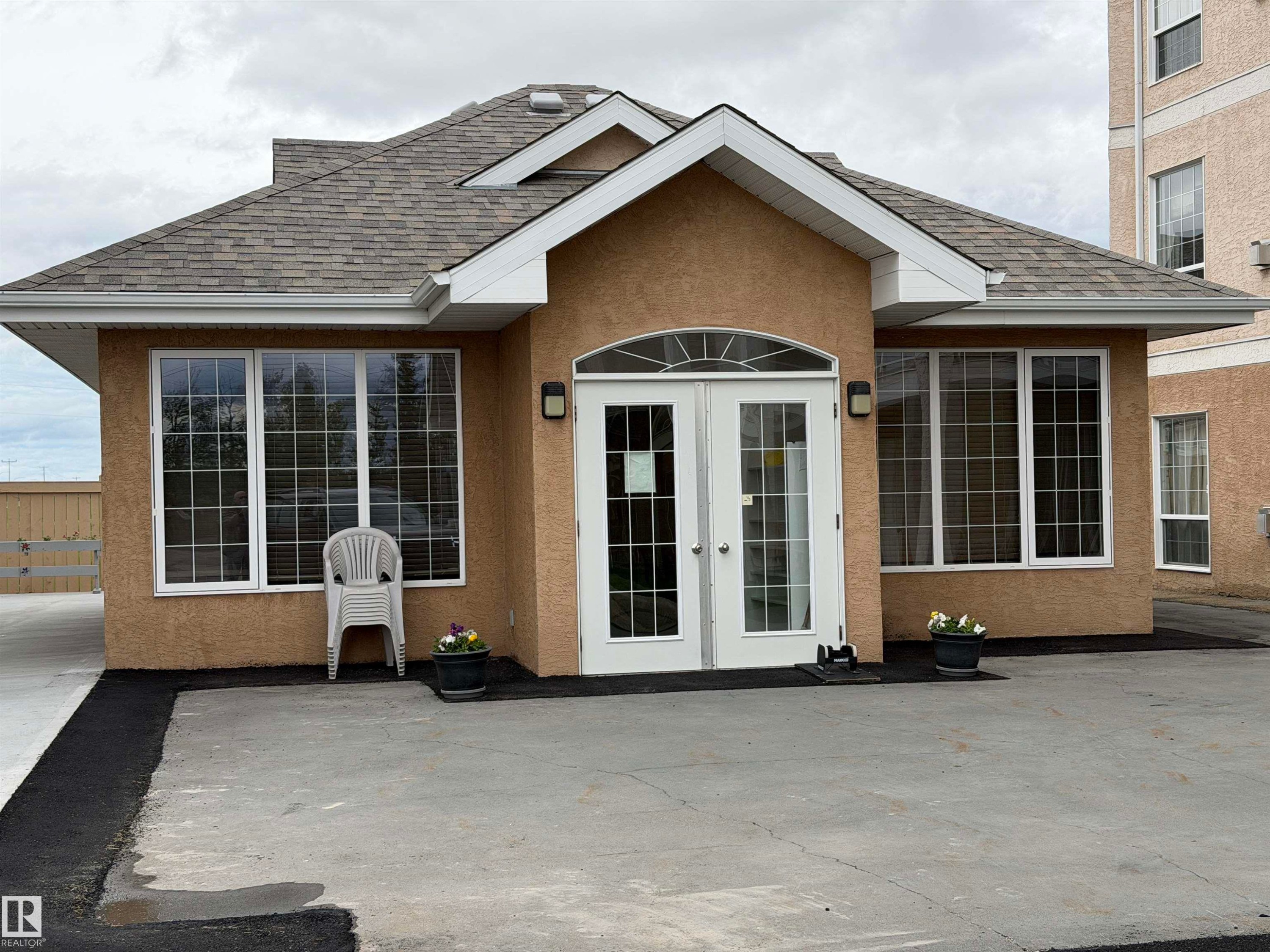 Stucco exterior building with a prominent arched double-door entry - 118 7801 Golf Course Road, Stony Plain, AB