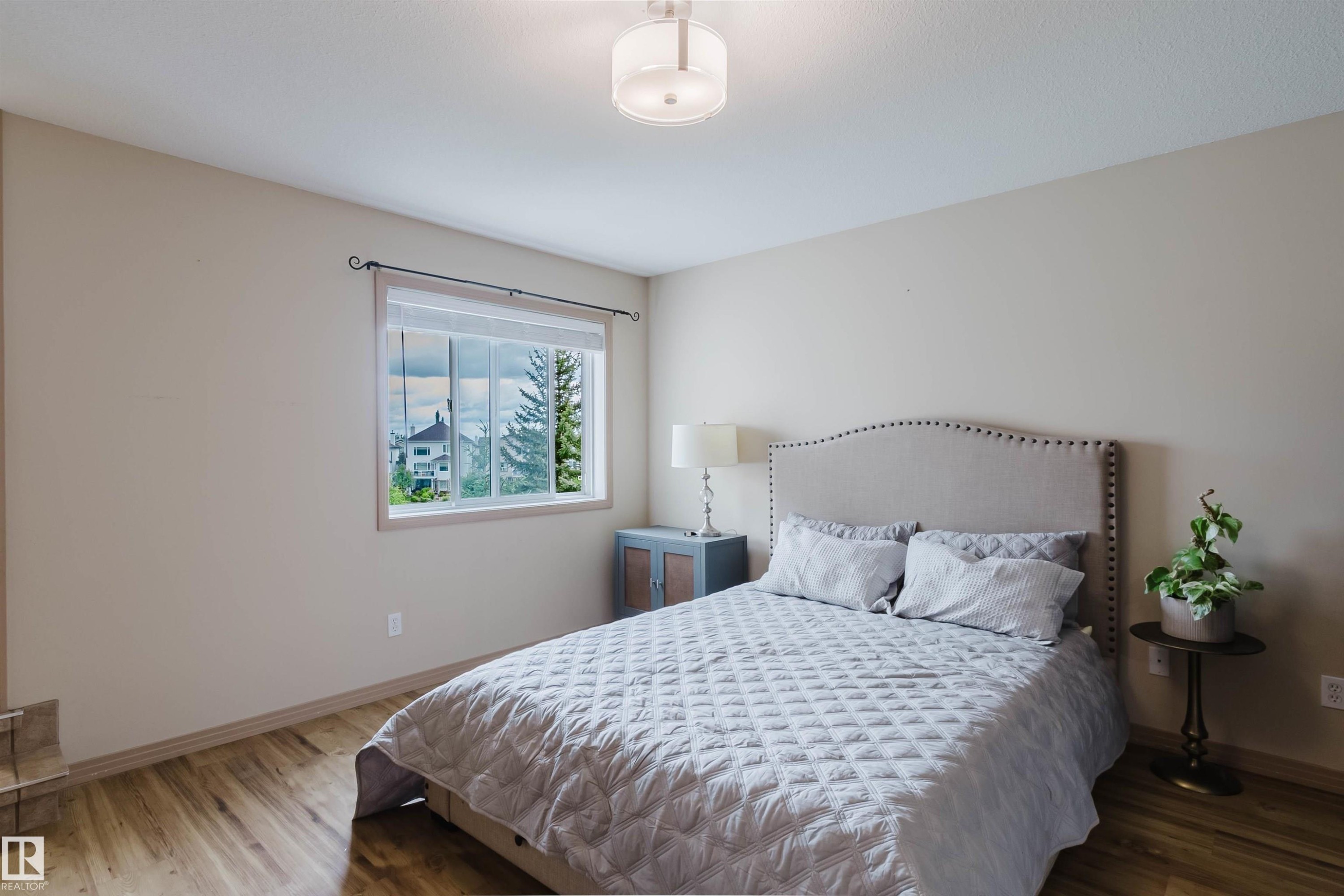 Spacious room featuring wood-finish flooring, neutral-toned walls, and a large window - 2236 Garnett Crest, Edmonton, AB