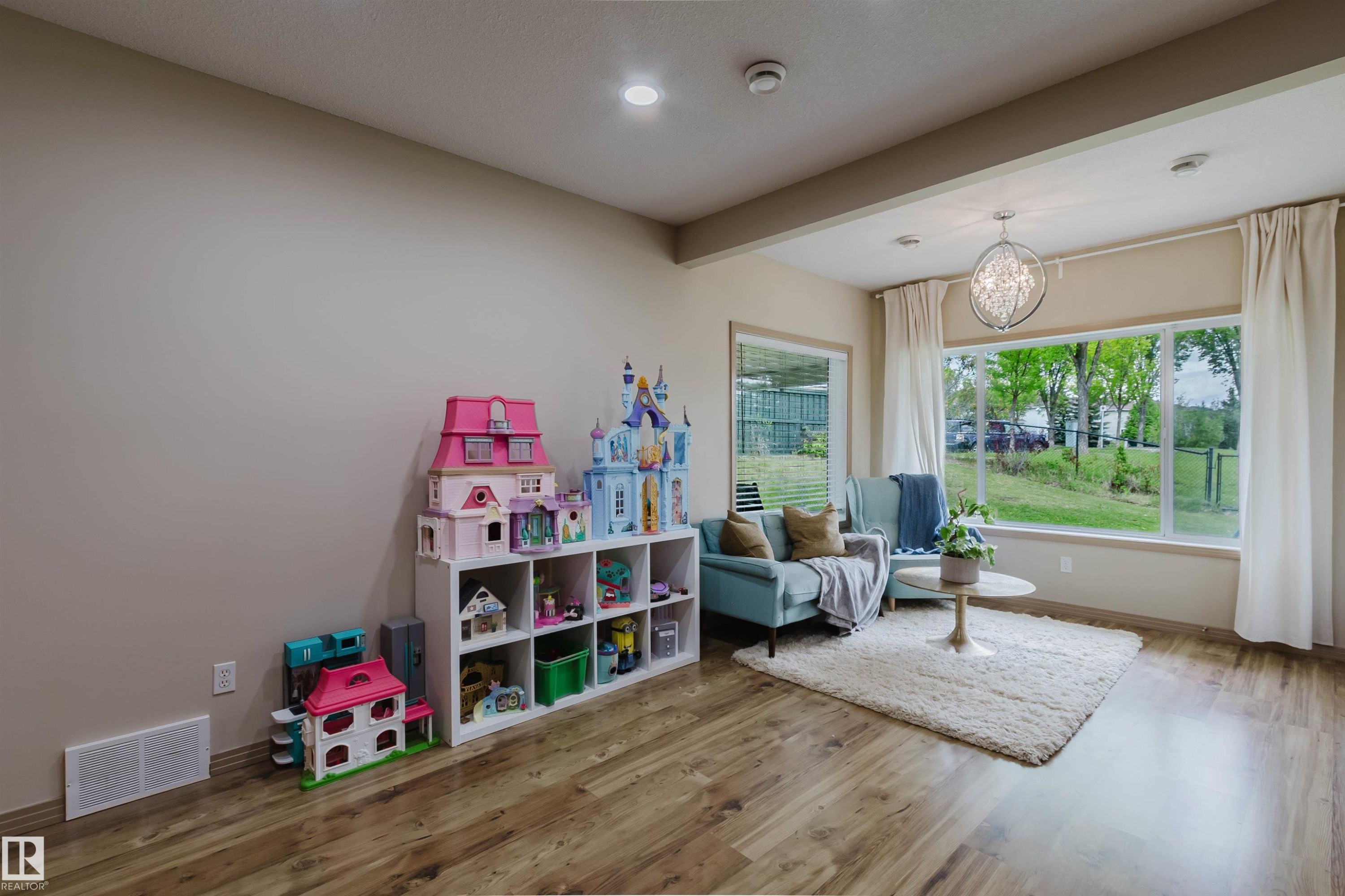 Open-concept living space featuring wood-finish flooring, recessed lighting, and expansive windows - 2236 Garnett Crest, Edmonton, AB