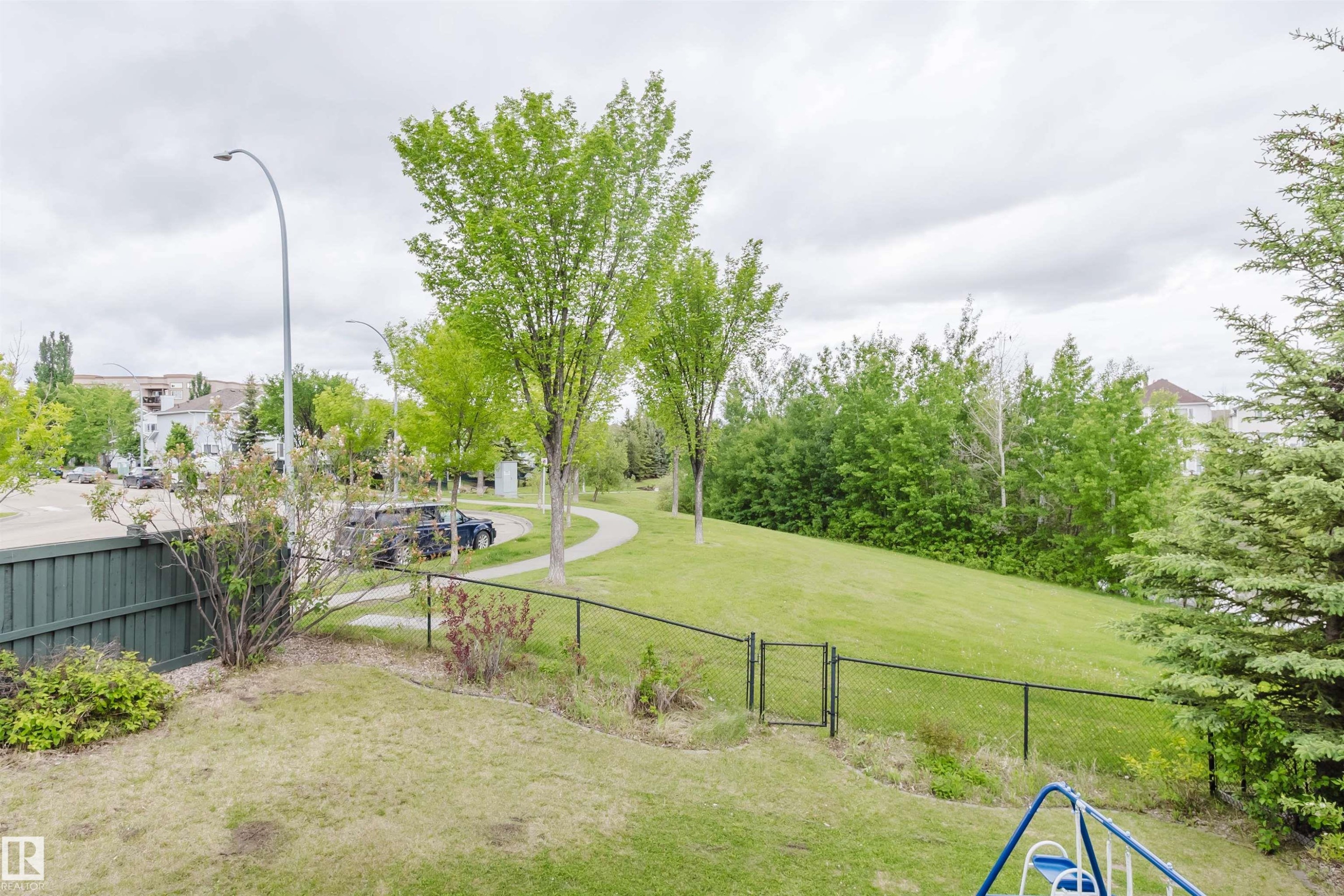 Expansive grassy yard with a dark green privacy fence and a chain link fence - 2236 Garnett Crest, Edmonton, AB