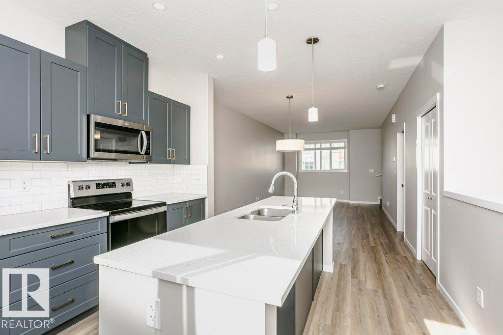 Contemporary kitchen featuring grey cabinetry, white countertops, a subway tile backsplash, and stainless steel appliances - 320 Secord Boulevard, Edmonton, AB - Indoor Photo Showing Kitchen With Stainless Steel Kitchen With Double Sink With Upgraded Kitchen
