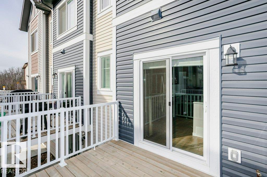 The property features a deck with white railings and a sliding glass door, providing access to the interior - 320 Secord Boulevard, Edmonton, AB - Outdoor With Exterior