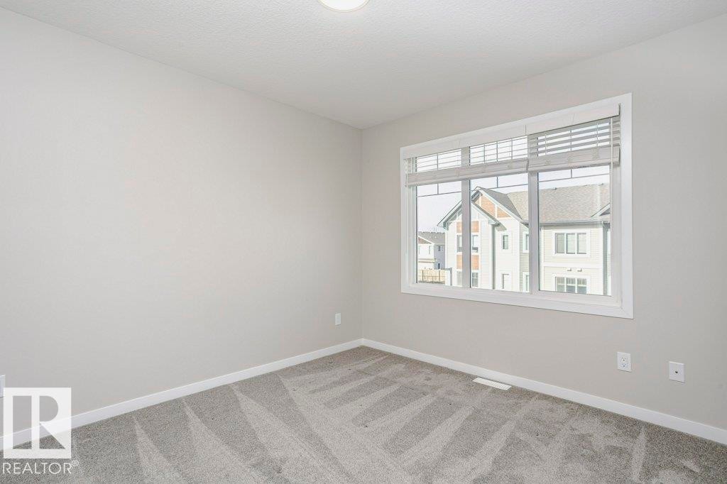 This room features light grey walls, a window with blinds, and grey patterned carpeting - 320 Secord Boulevard, Edmonton, AB - Indoor Photo Showing Other Room