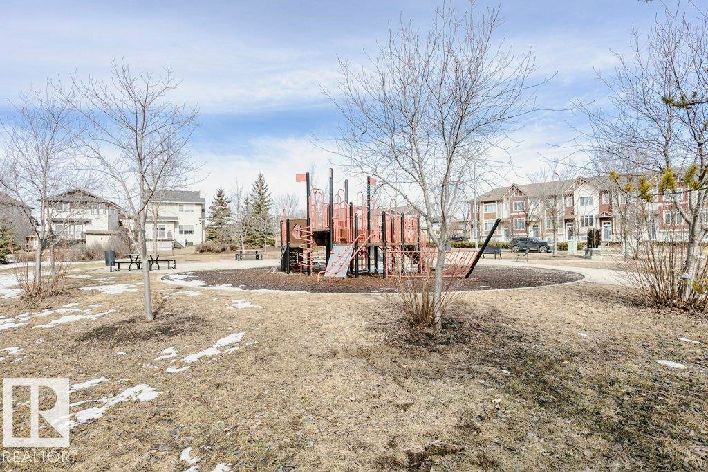 The property is situated within a community featuring a park with a playground structure and surrounding residential buildings - 320 Secord Boulevard, Edmonton, AB - Outdoor