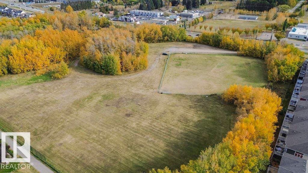 Expansive land parcel featuring open grassy areas and clusters of mature trees displaying autumn foliage - 320 Secord Boulevard, Edmonton, AB - Outdoor With View