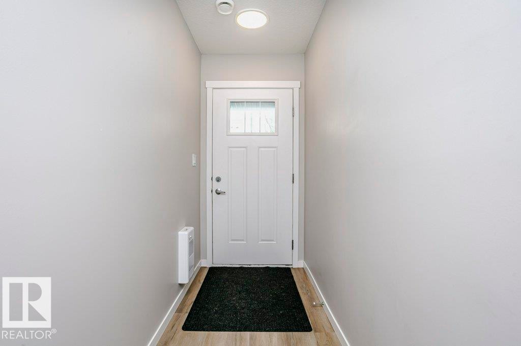 Entryway featuring light-colored walls, wood-look flooring, and a white front door with an integrated window - 320 Secord Boulevard, Edmonton, AB - Indoor Photo Showing Other Room