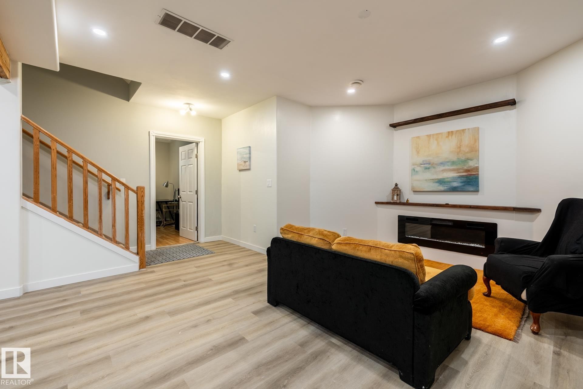 Living area featuring light wood-finish flooring, recessed lighting, and a built-in linear electric fireplace with a floating wooden mantel - 2036 Towne Centre Boulevard, Edmonton, AB - Indoor With Fireplace
