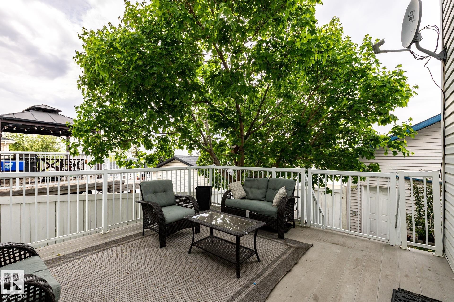 Spacious outdoor deck featuring a light gray outdoor area rug, white railing, mature tree canopy, and a visible gazebo structure - 2036 Towne Centre Boulevard, Edmonton, AB - Outdoor With Exterior