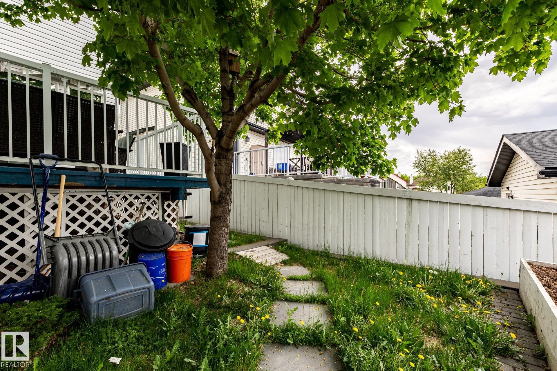 Side yard area featuring a mature tree, stepping stone pathway, and a white privacy fence - 2036 Towne Centre Boulevard, Edmonton, AB - Outdoor