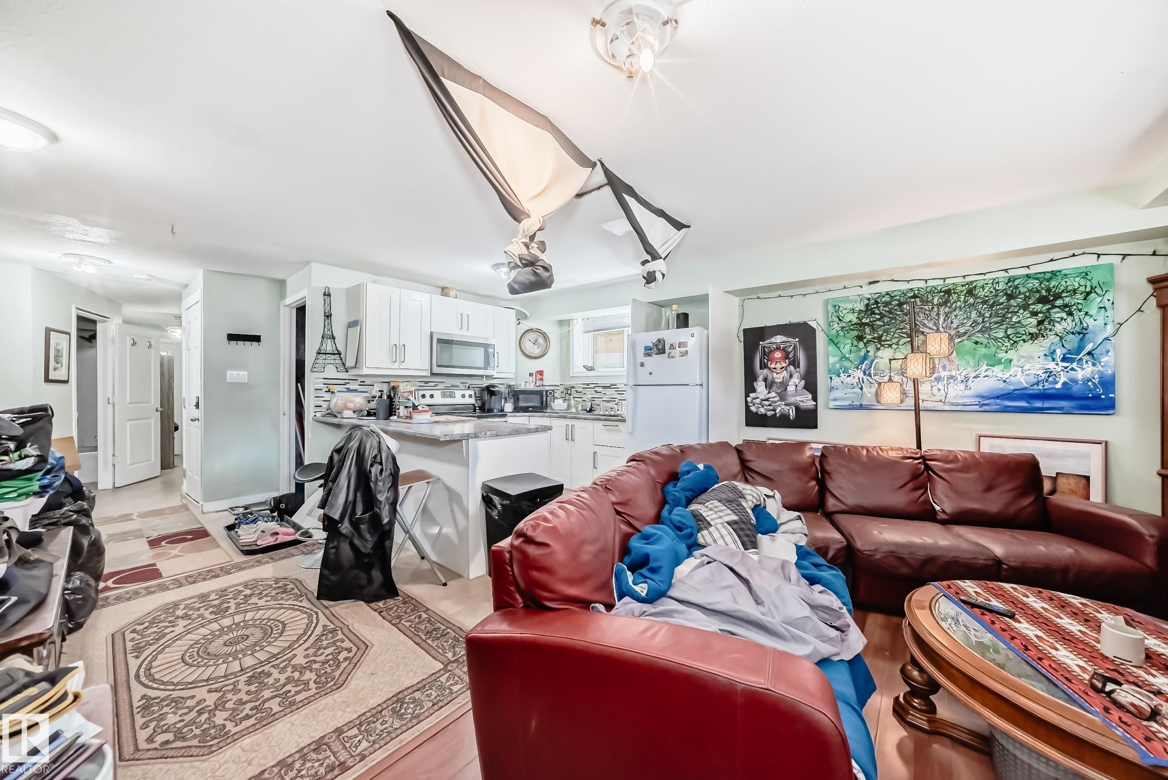 White cabinetry with stainless steel appliances and a tile backsplash in the kitchen area - 10017 153 Street, Edmonton, AB - Indoor Photo Showing Living Room