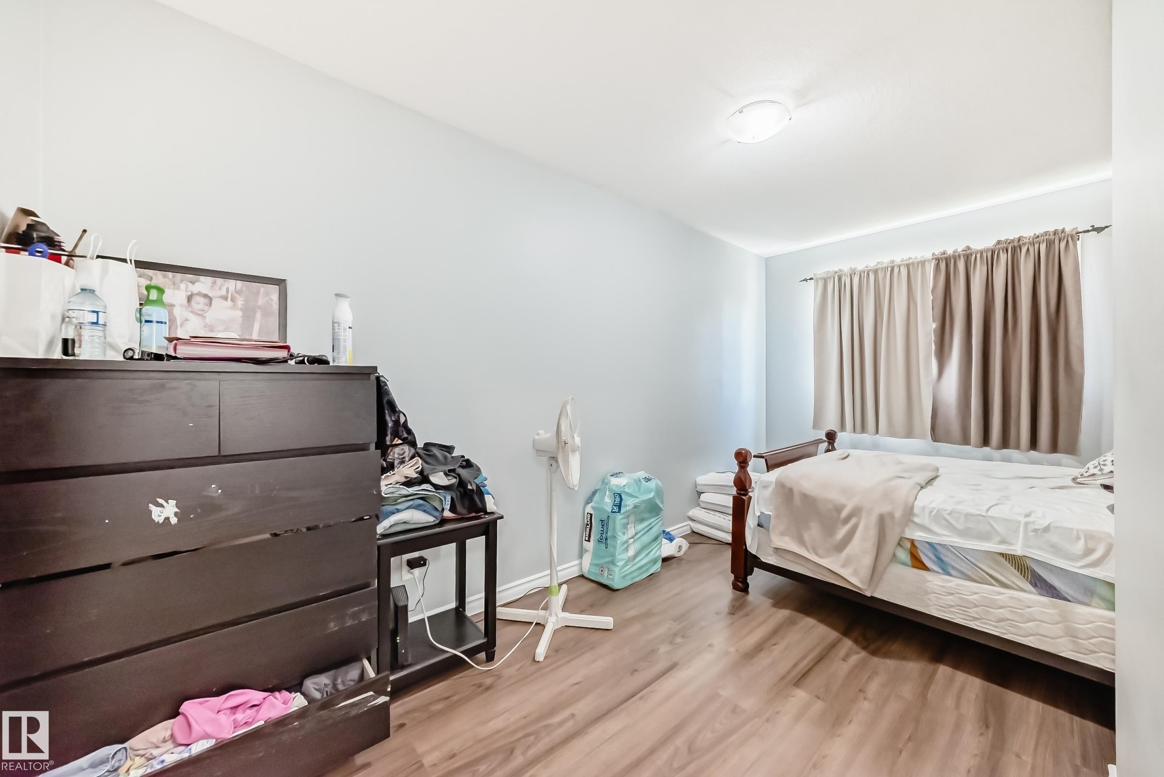 Room featuring wood-finish flooring, a neutral wall color, window with curtain rod and drapes, and an overhead flush-mount light fixture - 10017 153 Street, Edmonton, AB - Indoor Photo Showing Bedroom