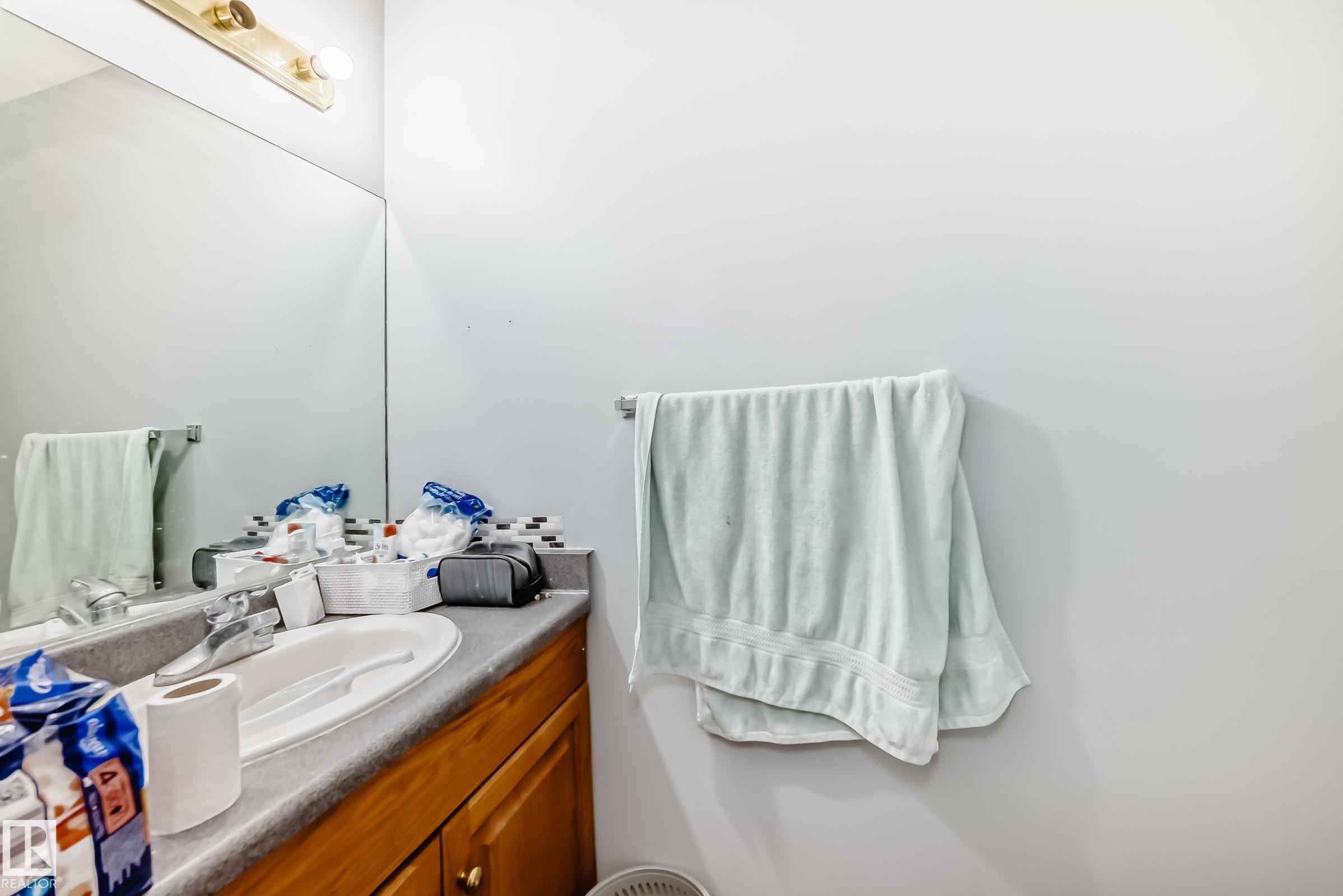 Bathroom vanity featuring a built-in sink, laminate countertop, wood-finish cabinetry, and mosaic tile backsplash - 10017 153 Street, Edmonton, AB - Indoor Photo Showing Bathroom