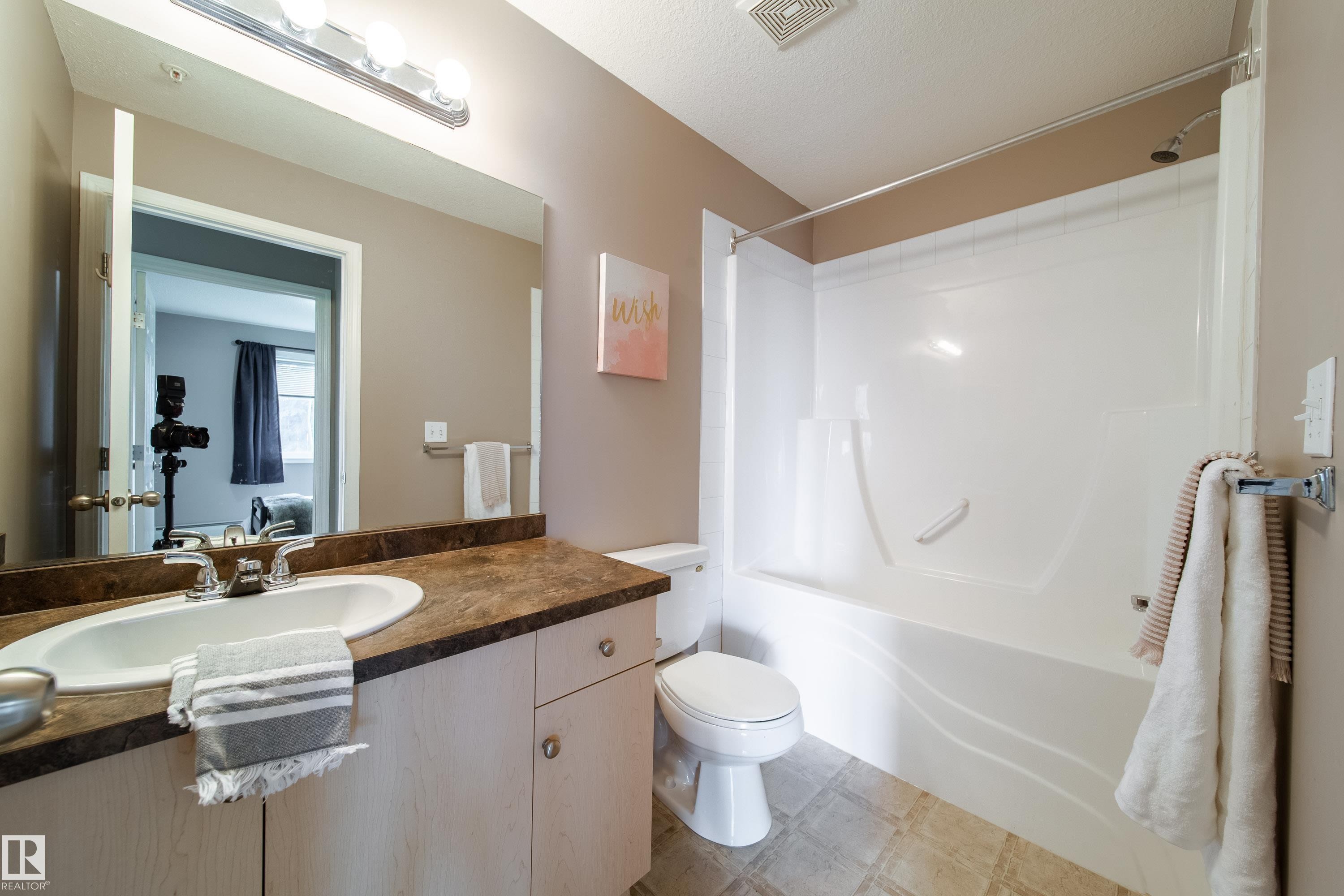 Bathroom featuring a single vanity with a laminate countertop, an undermount sink, and light wood cabinetry - 115 4309 33 Street, Stony Plain, AB