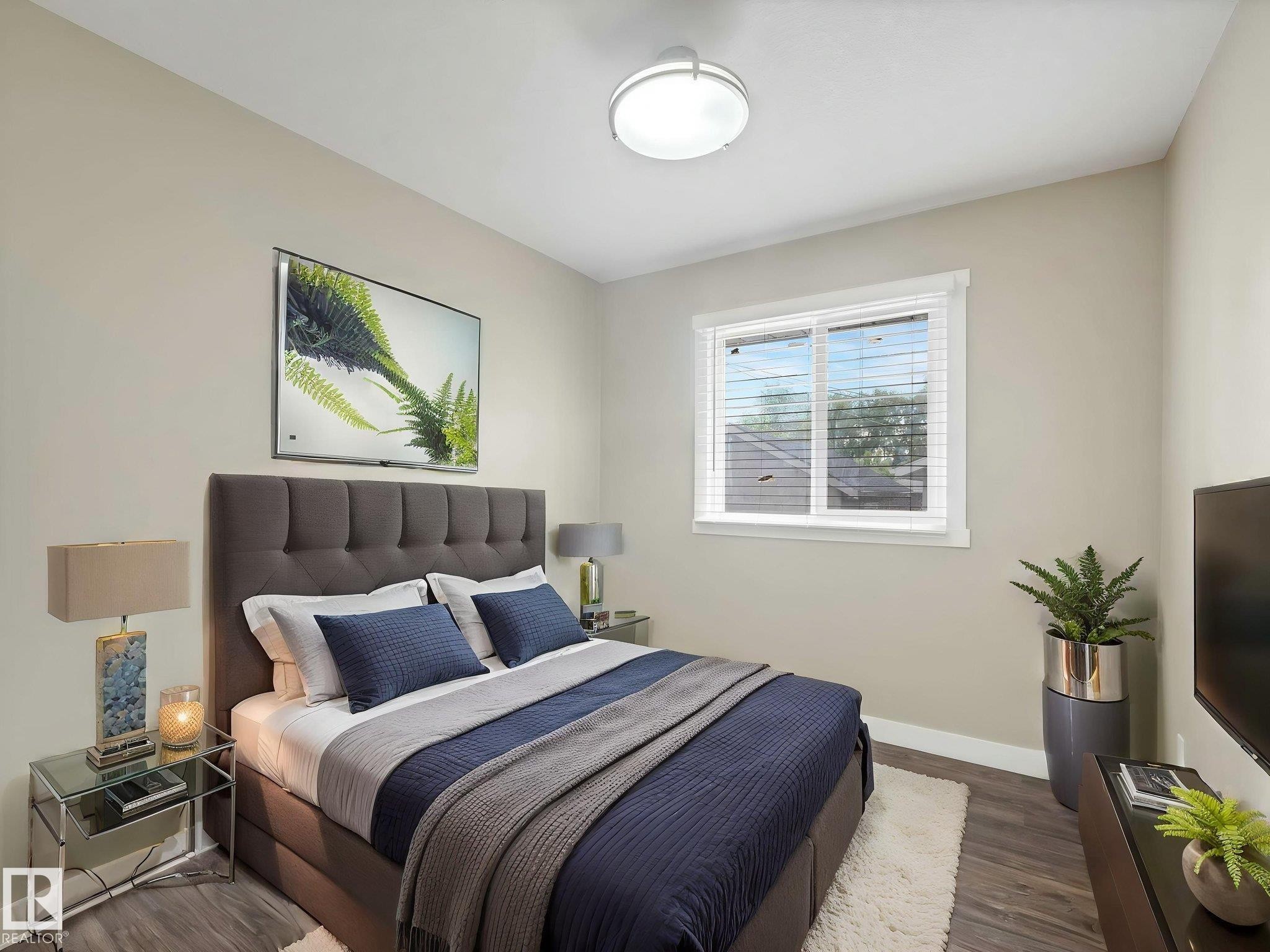 This room features wood-finish flooring, a contemporary ceiling light fixture, and a window with blinds - 12241 54 Street Nw, Edmonton, AB - Indoor Photo Showing Bedroom