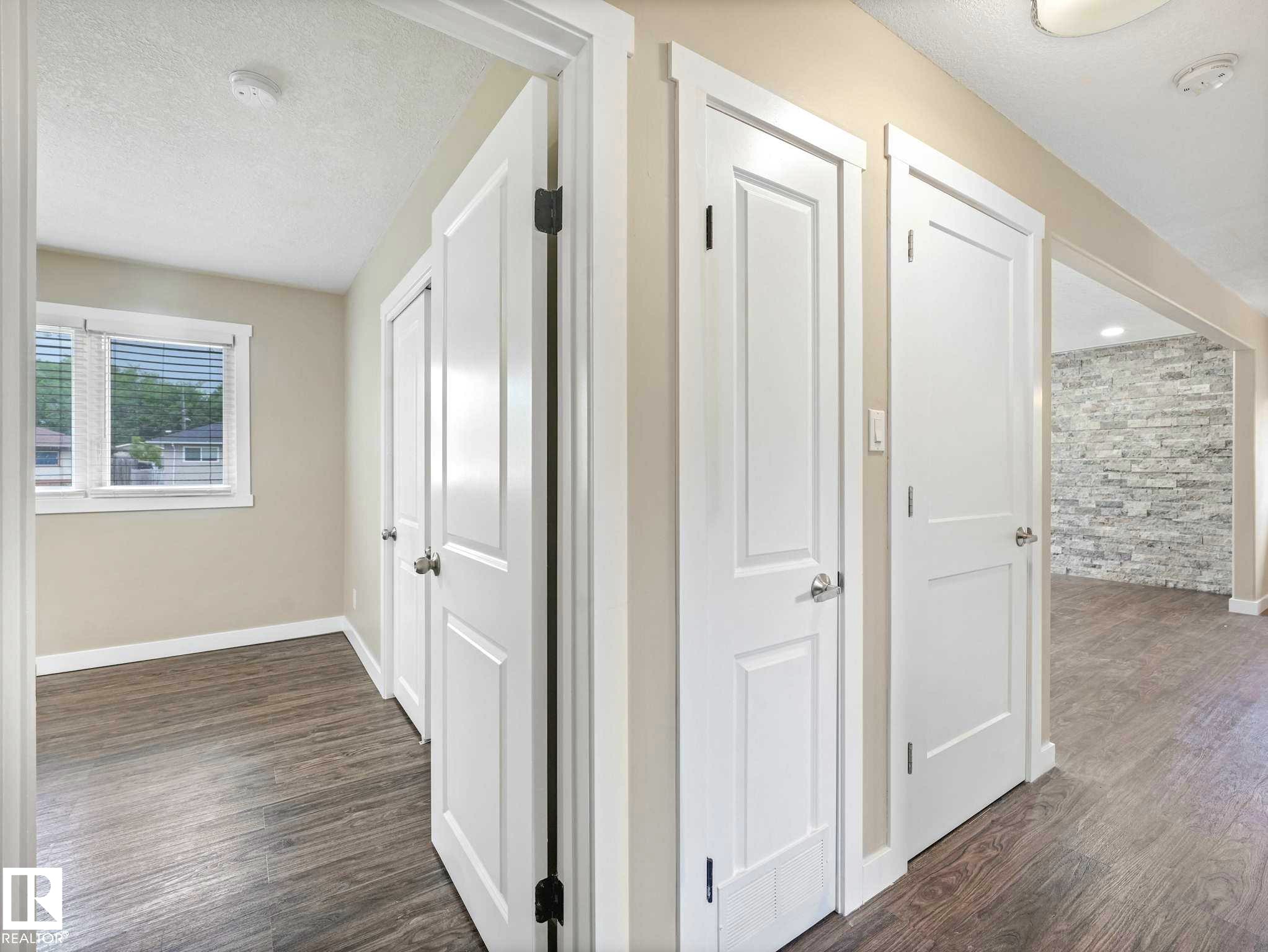 Interior hallway with wood-finish flooring, light neutral wall paint, and white trim - 12241 54 Street Nw, Edmonton, AB - Indoor Photo Showing Other Room