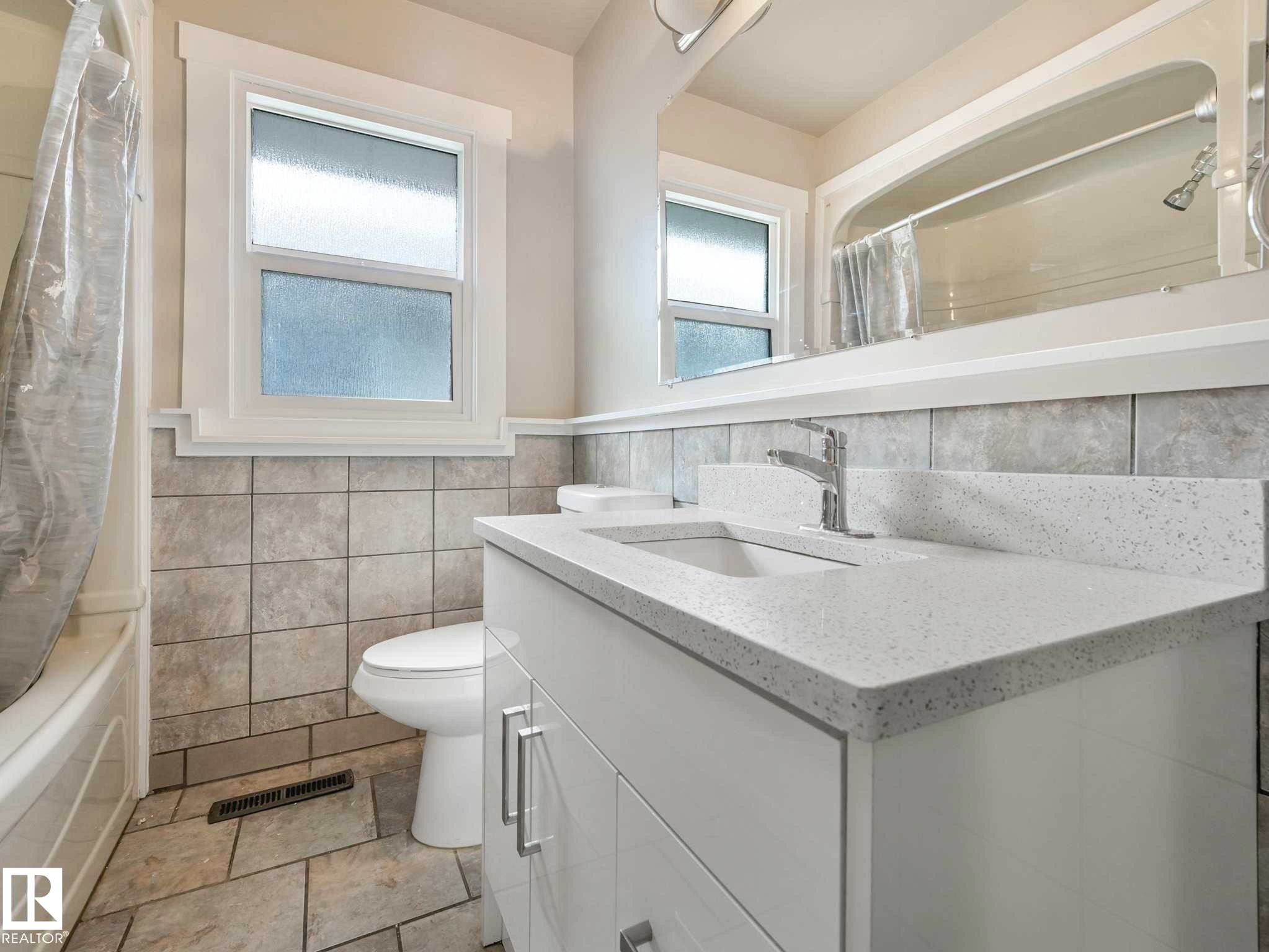 Bathroom featuring a white vanity with an integrated sink, polished chrome faucet, and a light-toned countertop - 12241 54 Street Nw, Edmonton, AB - Indoor Photo Showing Bathroom