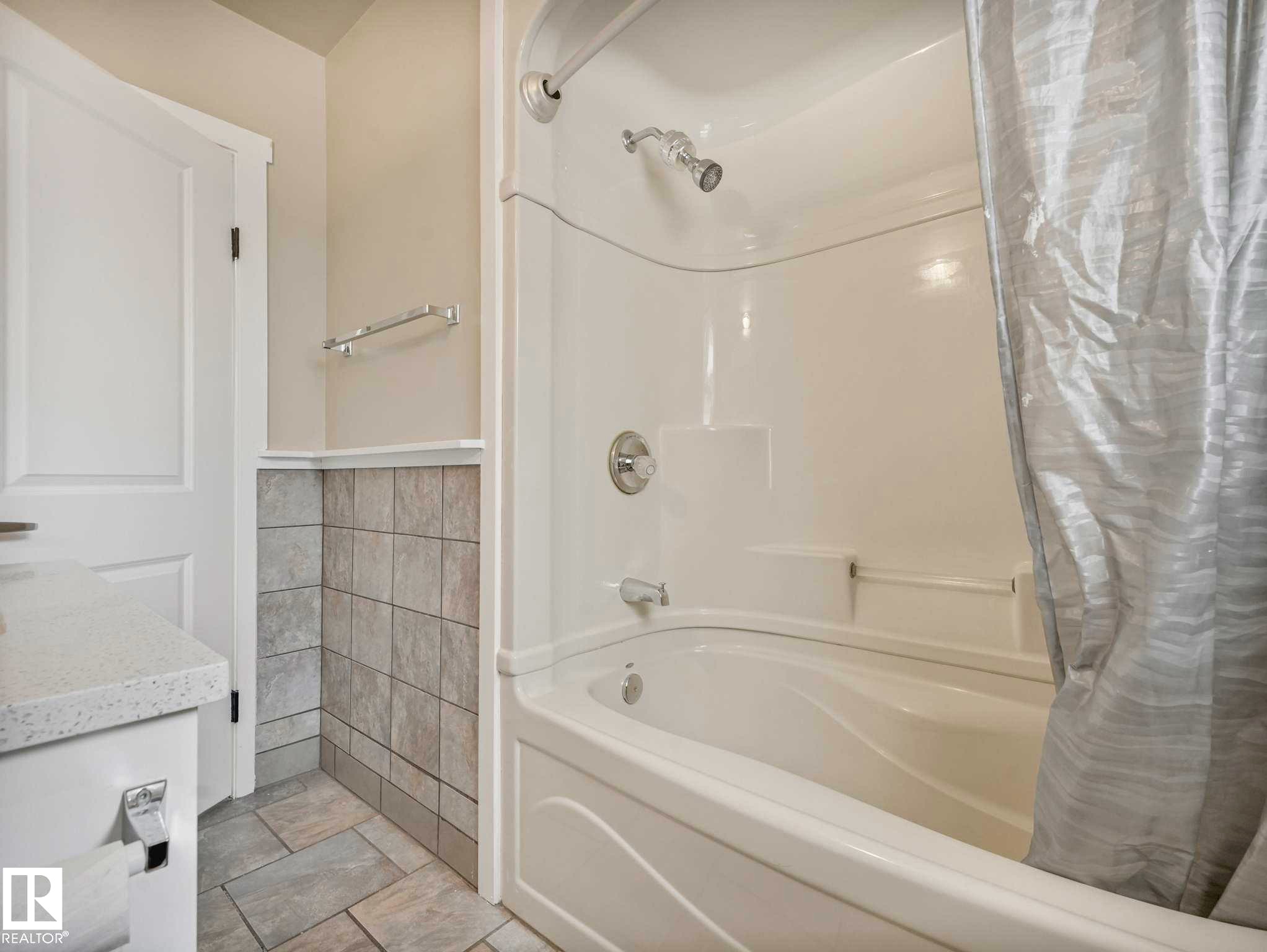 White acrylic bathtub and shower combination with chrome fixtures - 12241 54 Street Nw, Edmonton, AB - Indoor Photo Showing Bathroom