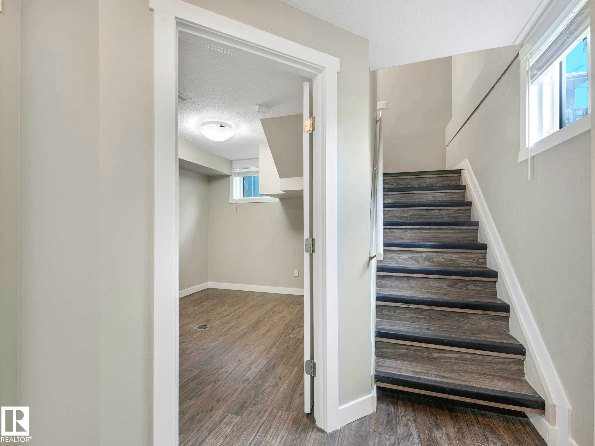 Wood-finish stairs with dark tread accents - 12241 54 Street Nw, Edmonton, AB - Indoor Photo Showing Other Room