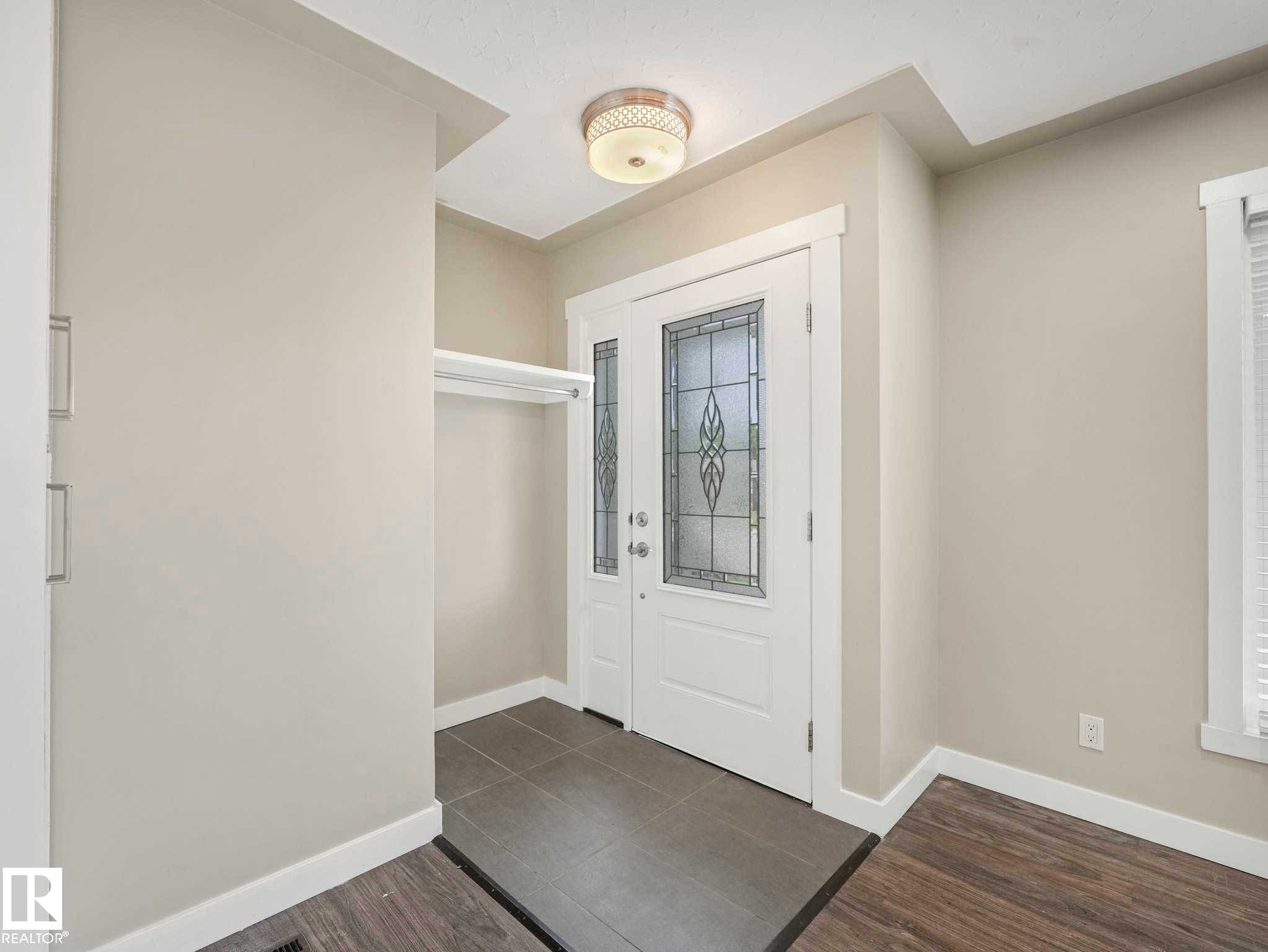 Entryway featuring a white door with decorative leaded glass, tile flooring, and a built-in coat rack - 12241 54 Street Nw, Edmonton, AB - Indoor Photo Showing Other Room