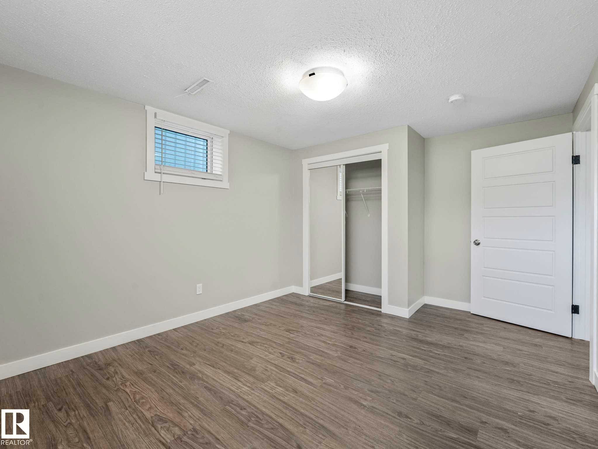 Light gray wood-finish flooring complements soft gray walls - 12241 54 Street Nw, Edmonton, AB - Indoor Photo Showing Other Room