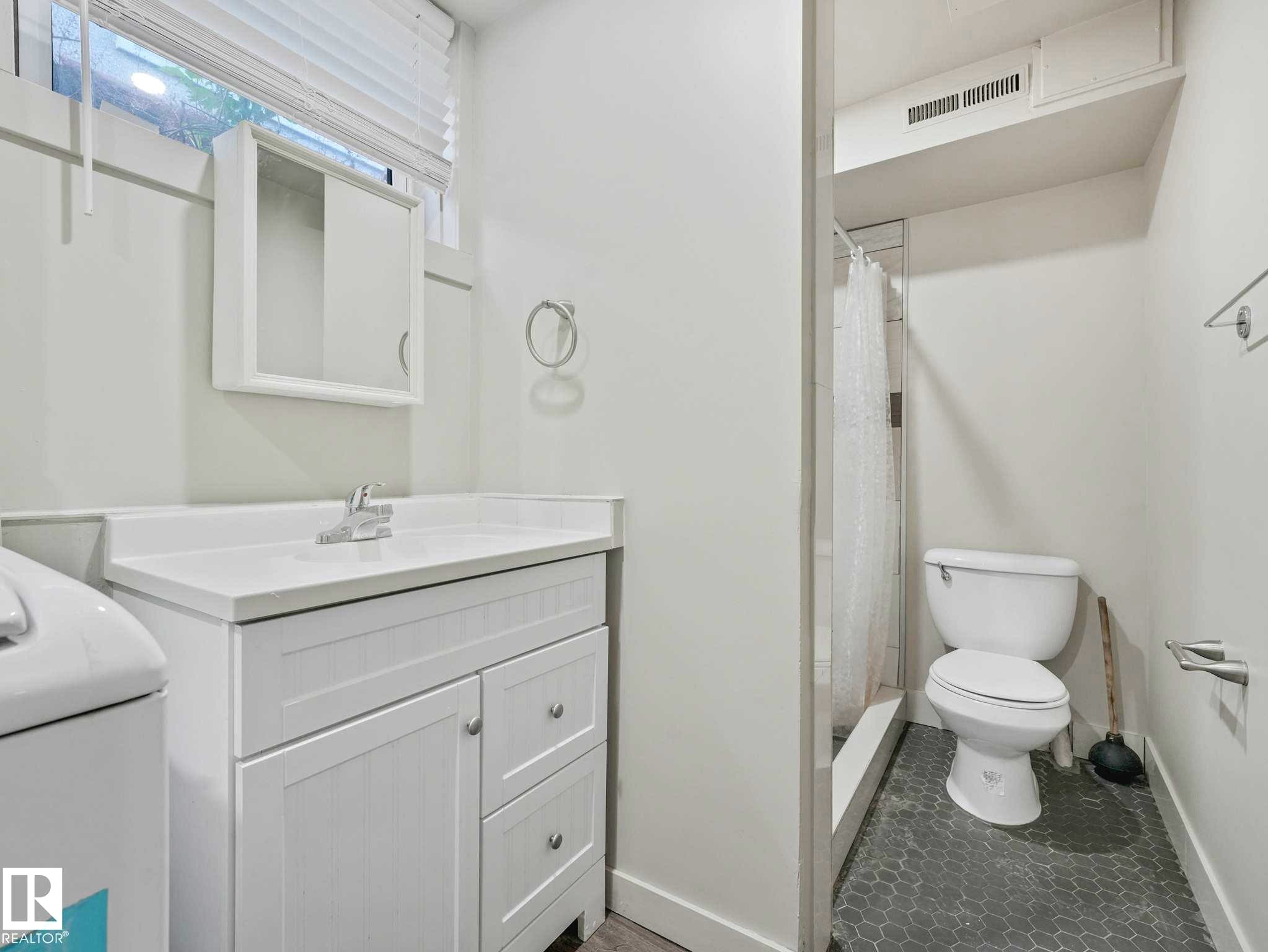 Bathroom featuring a white vanity with integrated sink, chrome faucet, wall-mounted medicine cabinet, and a window with blinds - 12241 54 Street Nw, Edmonton, AB - Indoor Photo Showing Bathroom