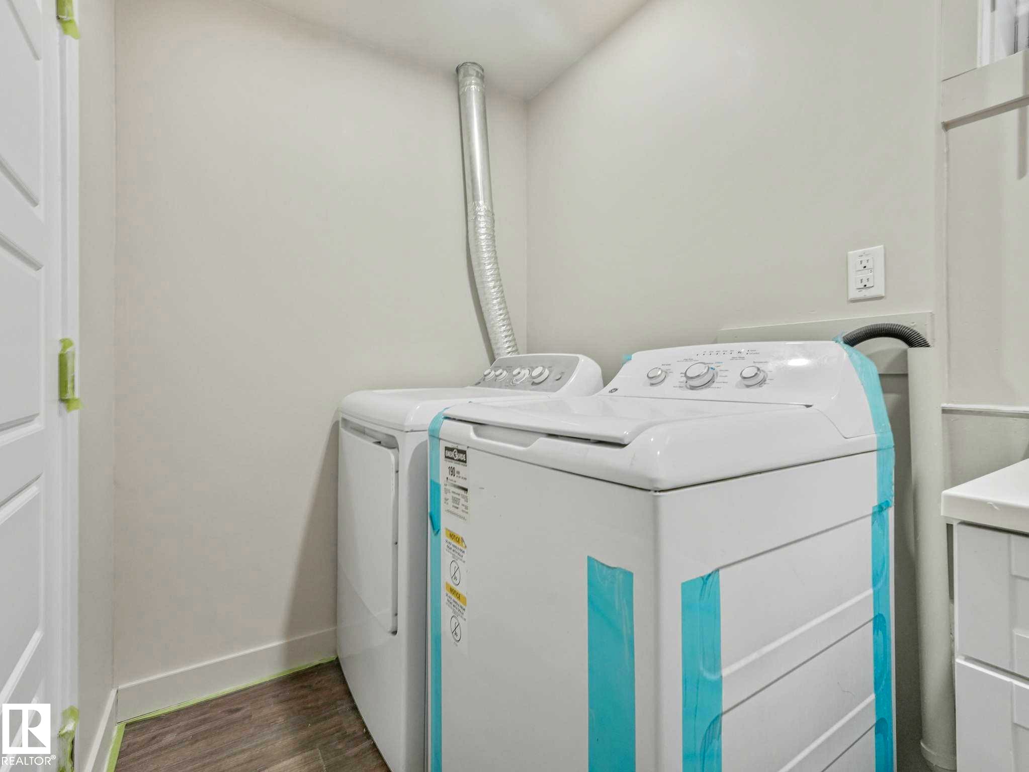 Dedicated laundry area featuring wood-finish flooring and white painted walls - 12241 54 Street Nw, Edmonton, AB - Indoor Photo Showing Laundry Room