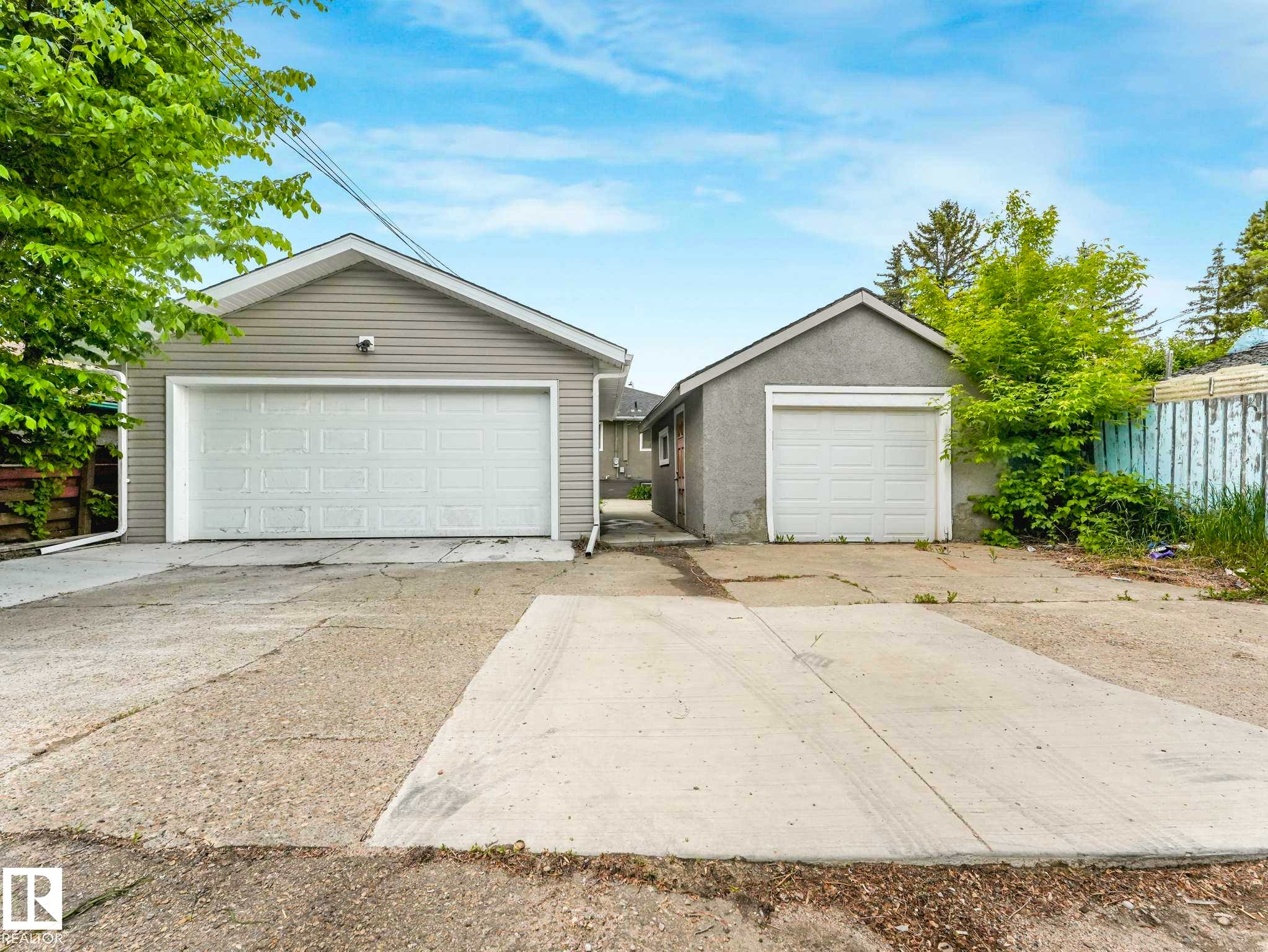 Two detached garages, one with light gray siding and a white panel garage door, the other with gray stucco and a white panel garage door - 12241 54 Street Nw, Edmonton, AB - Outdoor