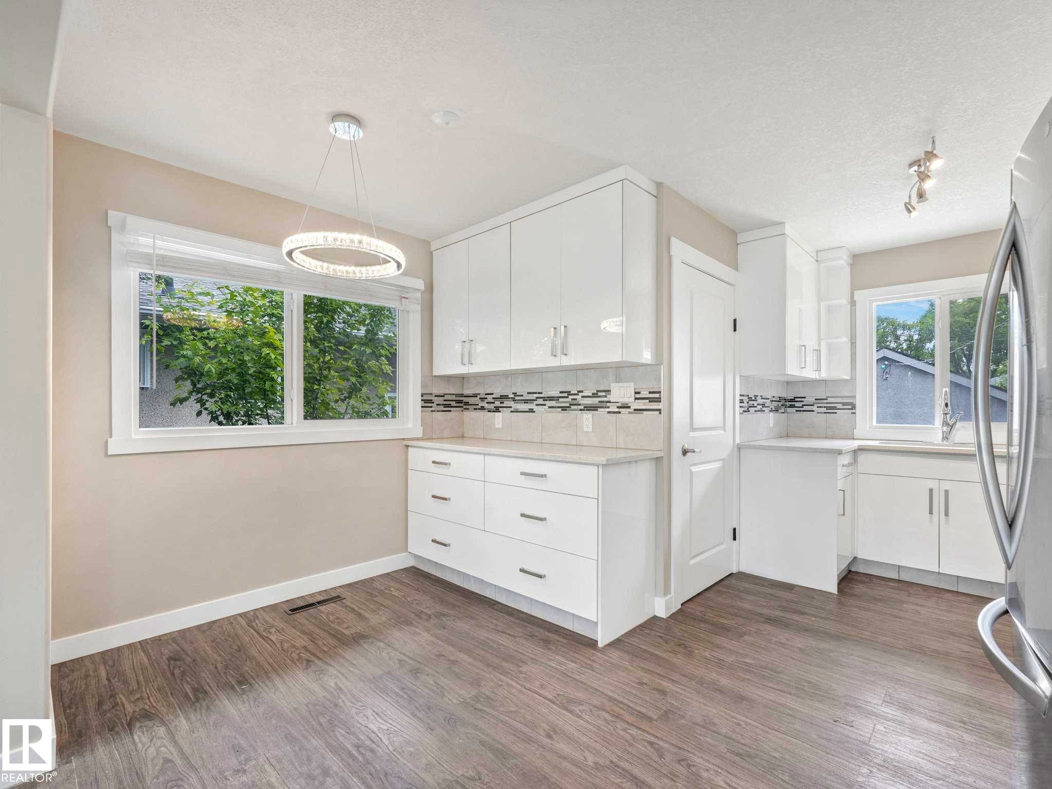 Kitchen area featuring white cabinetry, light countertops, and wood-finish flooring - 12241 54 Street Nw, Edmonton, AB - Indoor Photo Showing Other Room