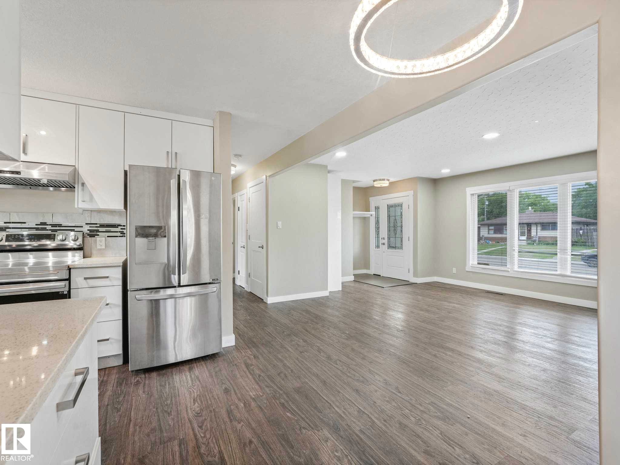 Open-concept living space featuring wood-finish flooring, a modern chandelier, and recessed lighting - 12241 54 Street Nw, Edmonton, AB - Indoor Photo Showing Kitchen